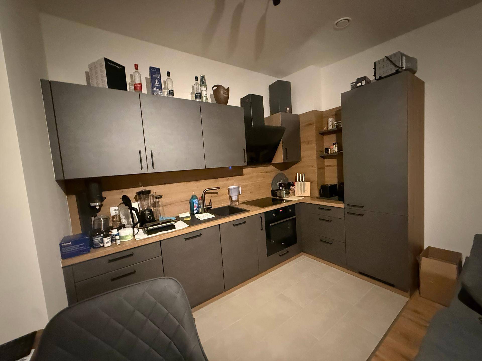 Moderne Einbauküche mit grauen Schränken, Holz-Arbeitsplatte und integrierten Geräten.