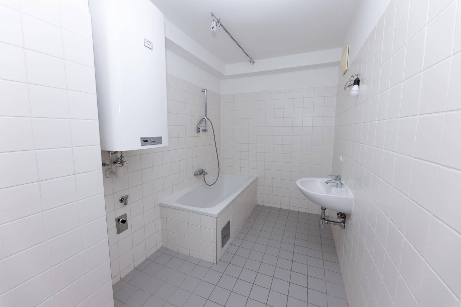 Badezimmer mit Badewanne, Waschbecken und weißen Fliesen.