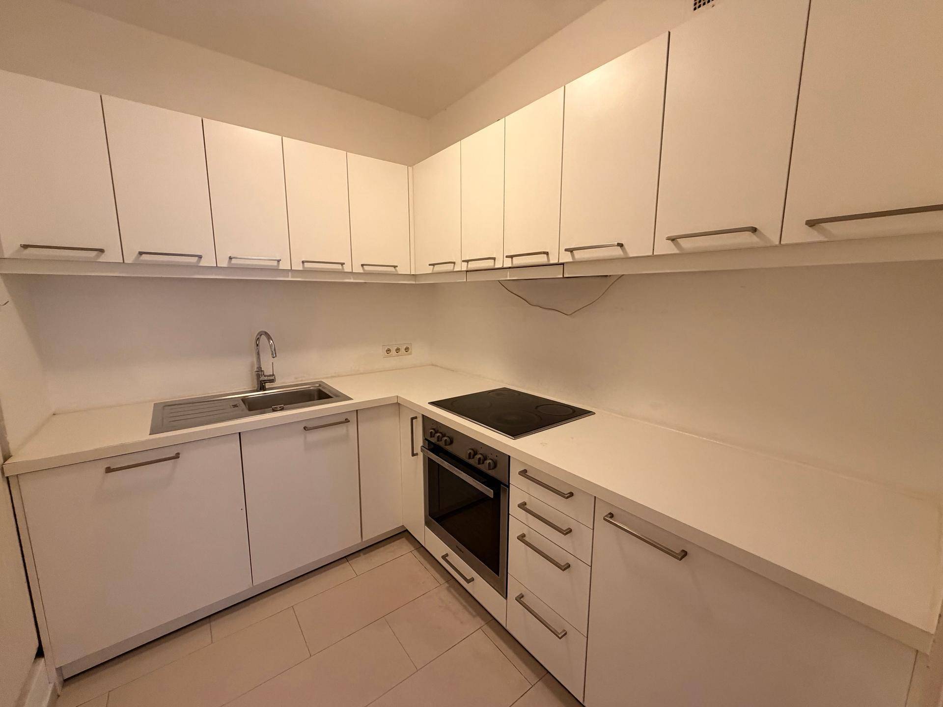 Moderne Einbauküche in Weiß mit Induktionskochfeld, Backofen und ausreichend Stauraum.