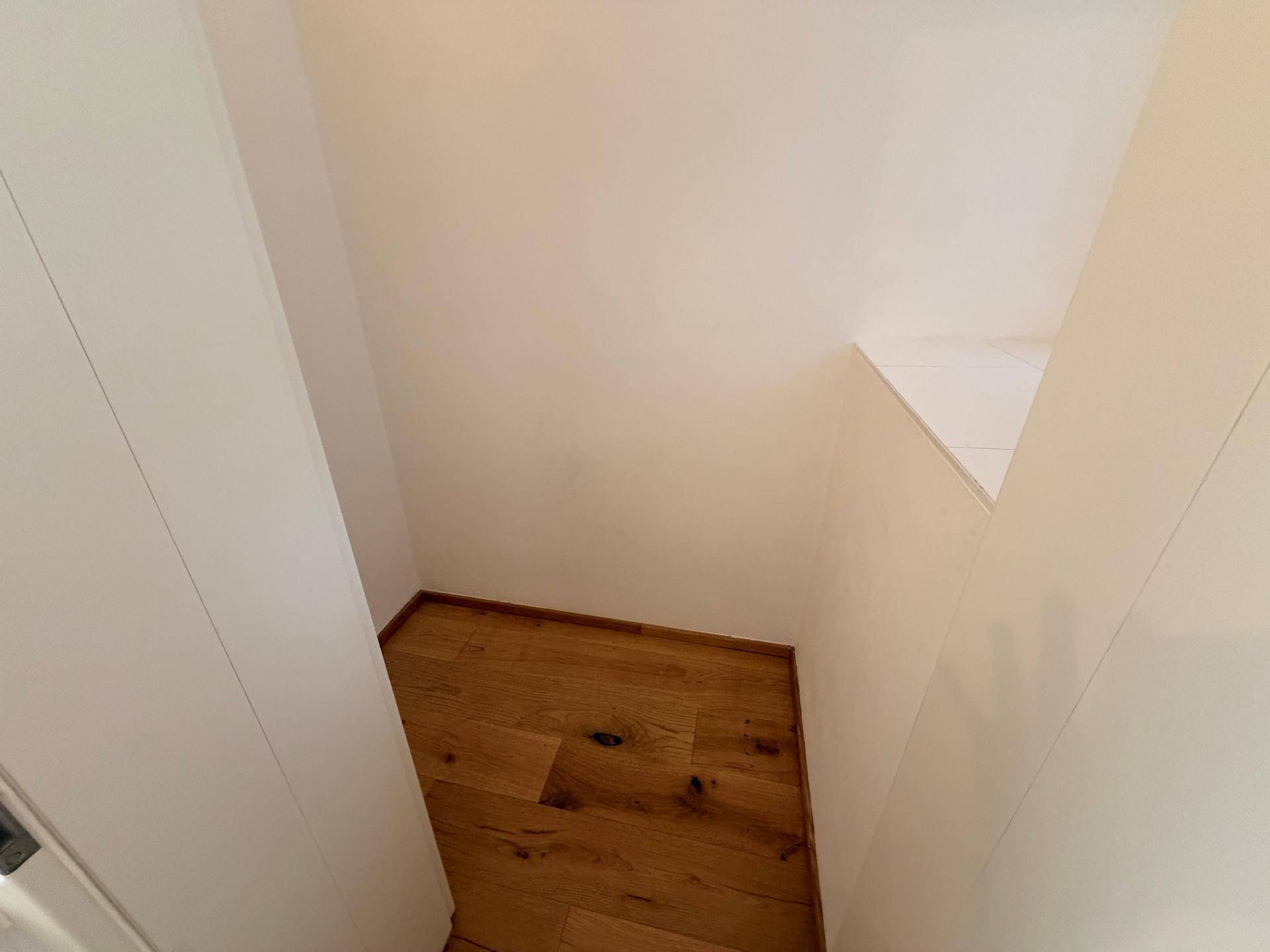 Kleiner Abstellraum oder Nische mit Holzboden und weißen Wänden.
