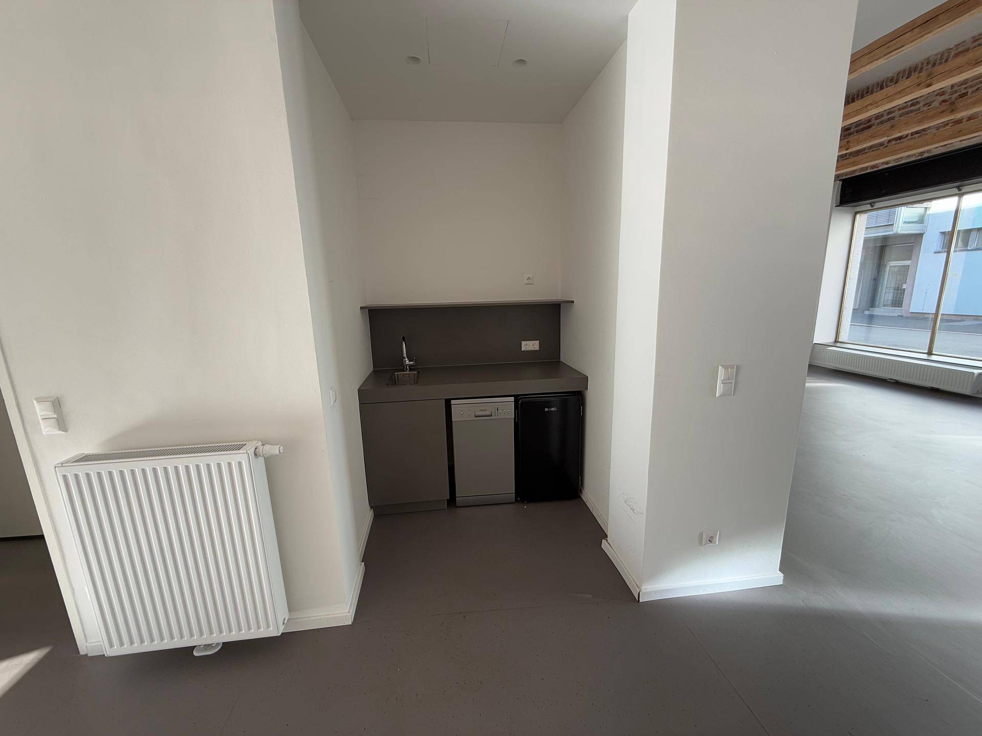 Kleine Küchenzeile in einer Nische mit Spüle, Kühlschrank und Geschirrspüler.
