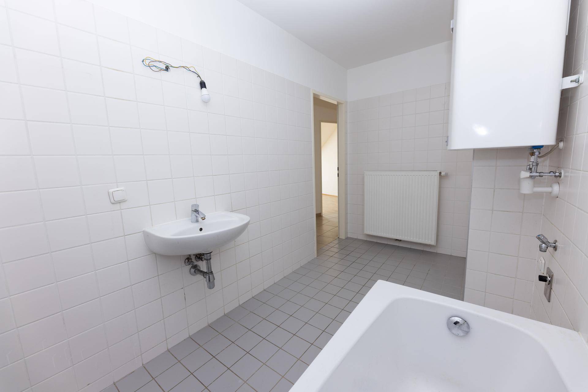 Helles Badezimmer mit Waschbecken, Badewanne und weißen Wandfliesen.