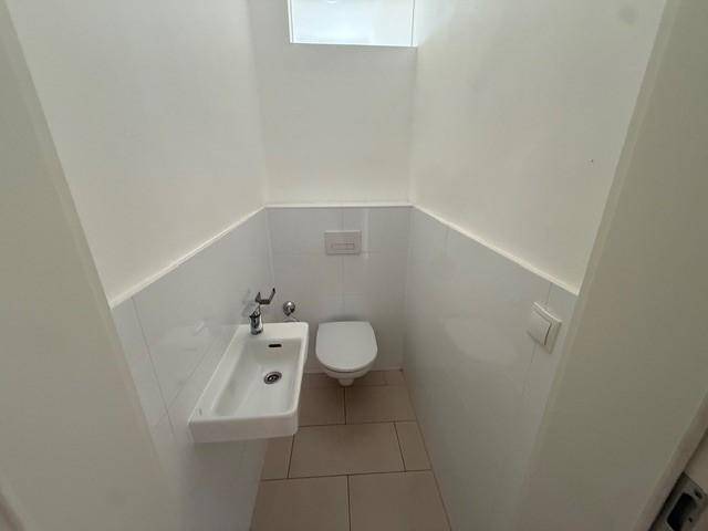 Modernes Gäste-WC mit wandhängendem WC und kleinem Waschbecken.