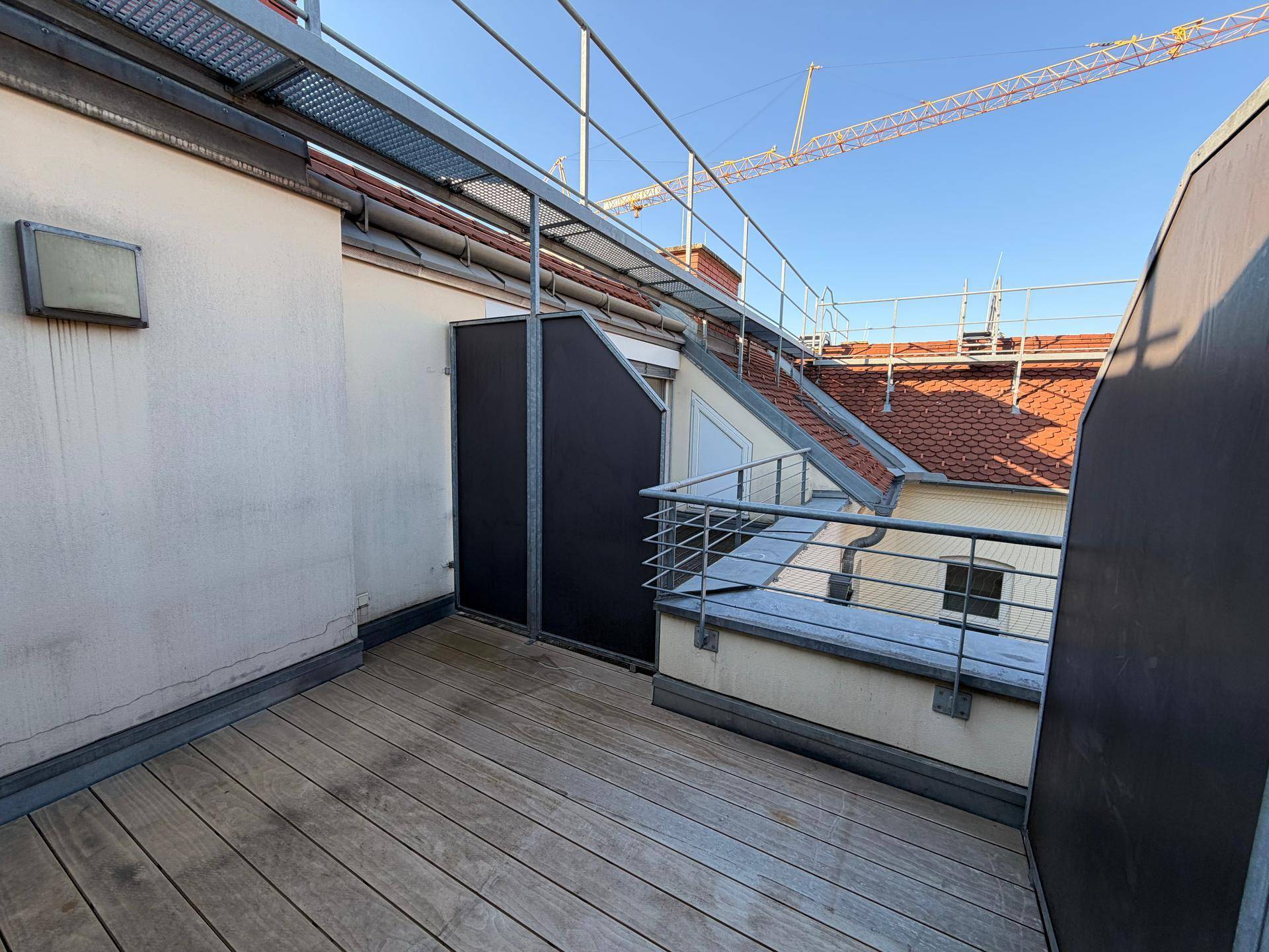 Geräumige Dachterrasse mit Holzboden und Metallgeländer, ideal für entspannte Stunden im Freien.