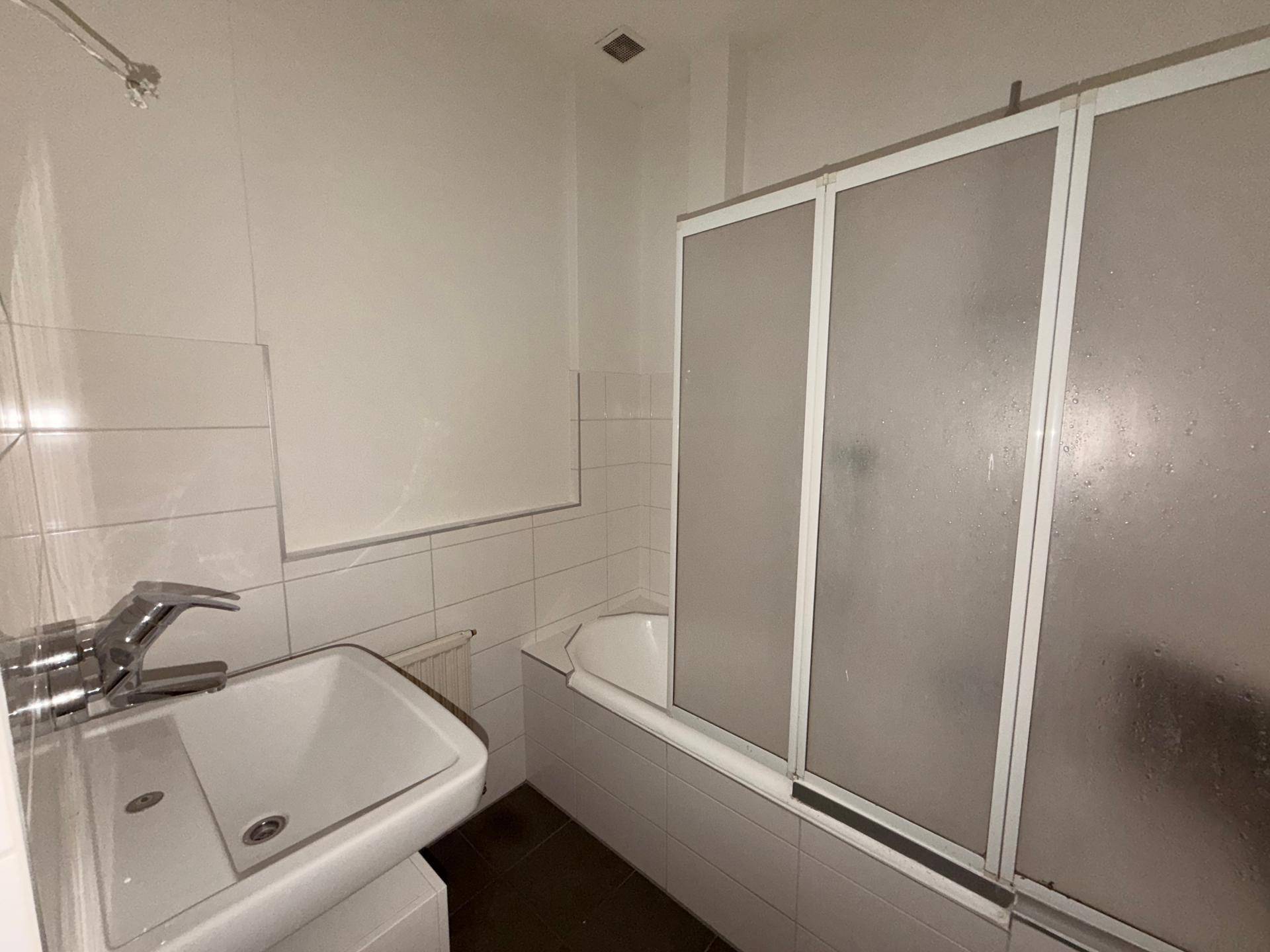 Badezimmer mit Badewanne, Duschabtrennung und weiß gefliesten Wänden.
