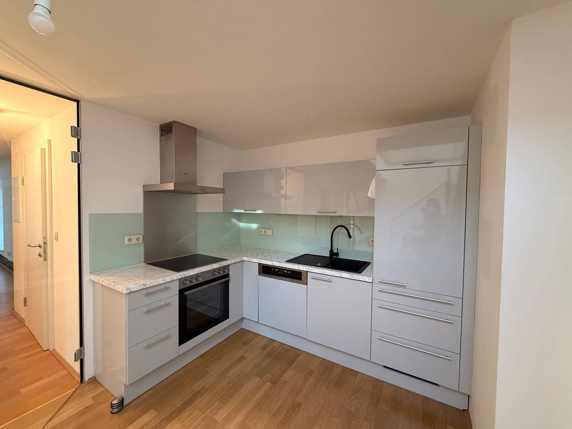 Helle Einbauküche mit modernen Geräten, glänzenden Oberflächen und praktischem Design.