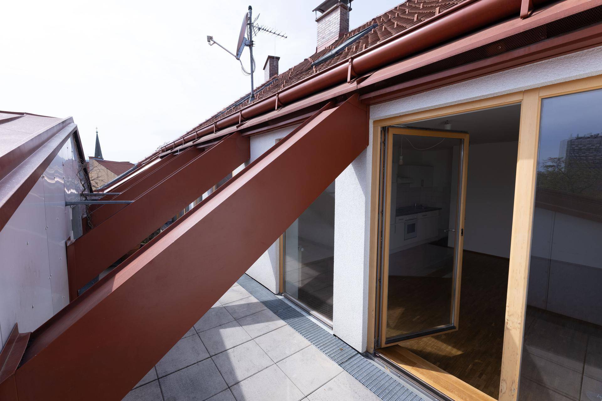 Geräumige Dachterrasse mit Fliesenboden und Zugang zum Innenbereich.