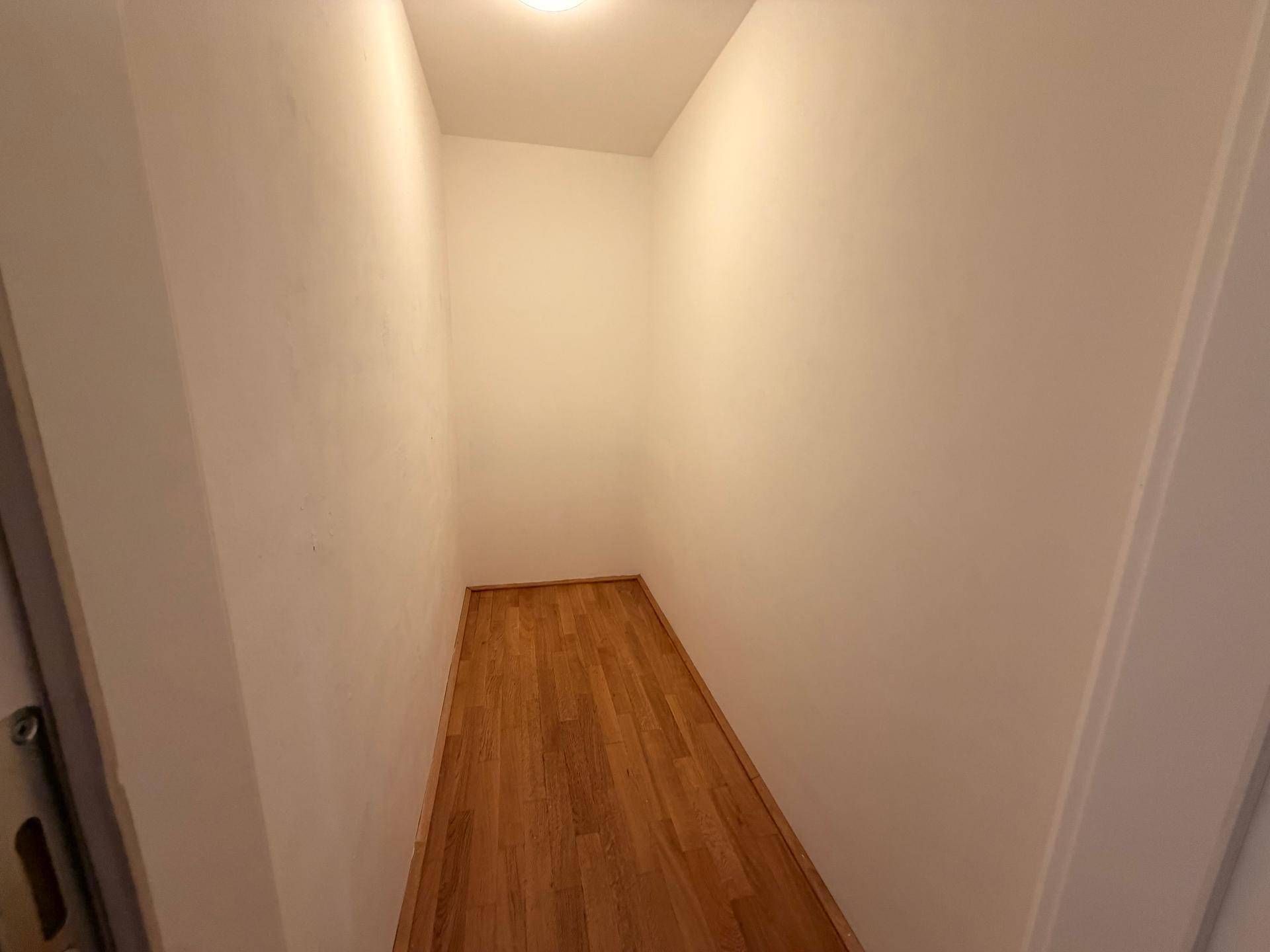 Praktischer Abstellraum mit Holzboden und weißen Wänden für zusätzlichen Stauraum.