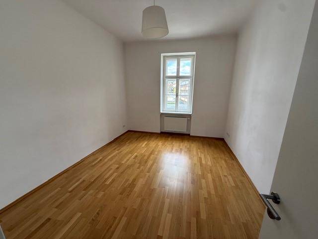 Freundlicher Raum mit Parkettboden und einem Fenster, das für gute Belichtung sorgt.