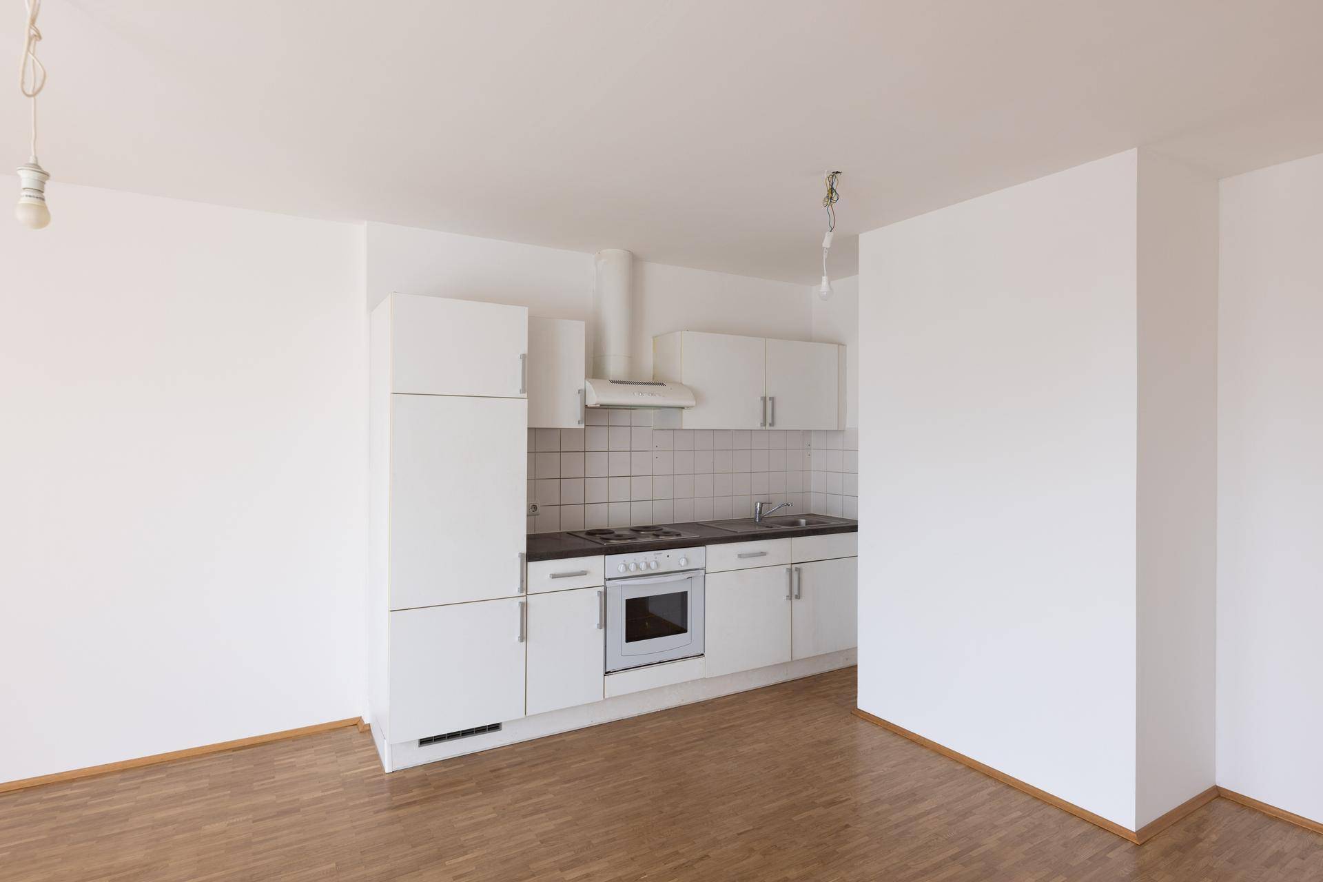 Funktionale Einbauküche mit weißen Schränken, Elektroherd und Fliesenrückwand.