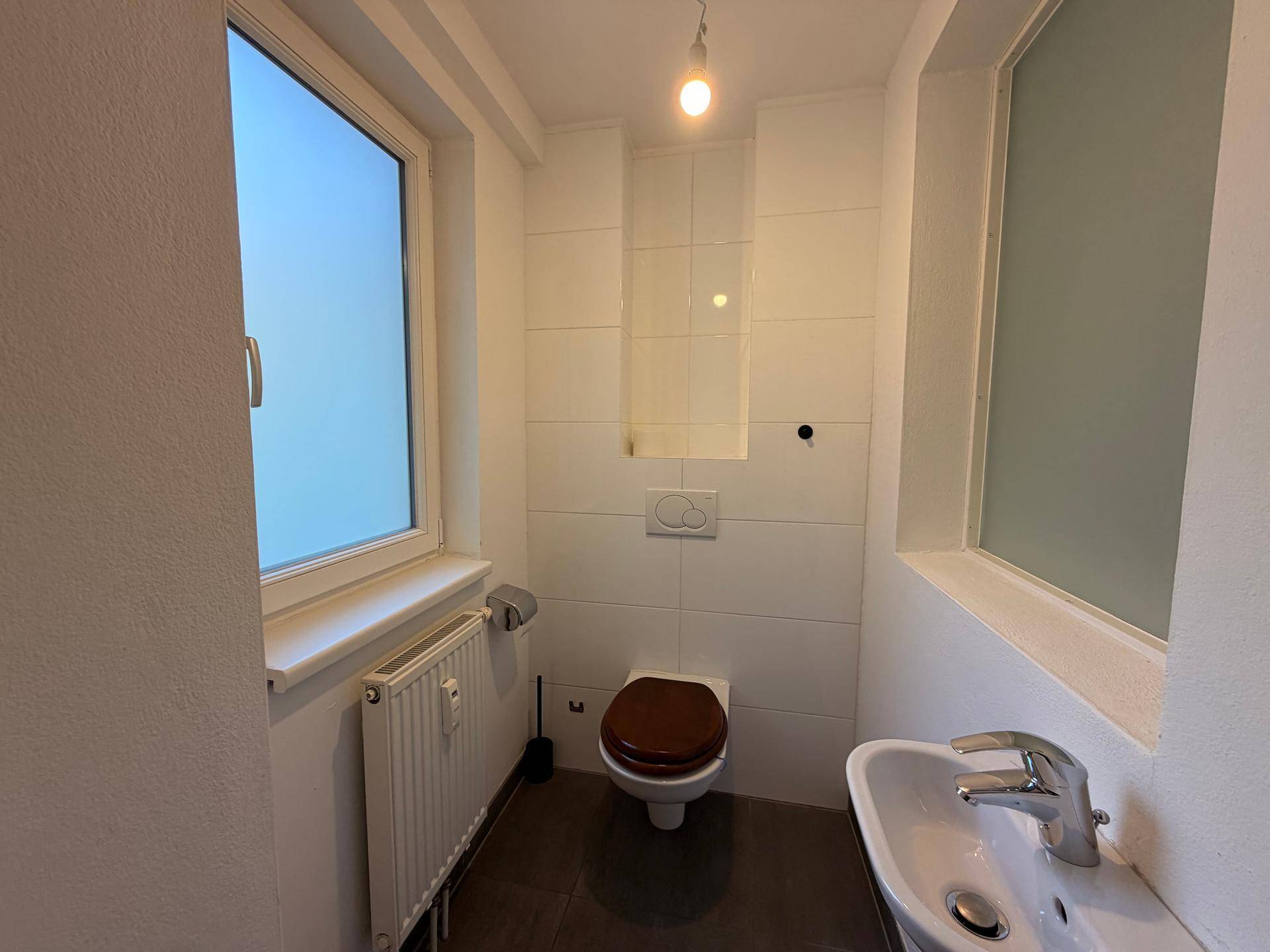 Kleines Gäste-WC mit Fenster, WC und Handwaschbecken.