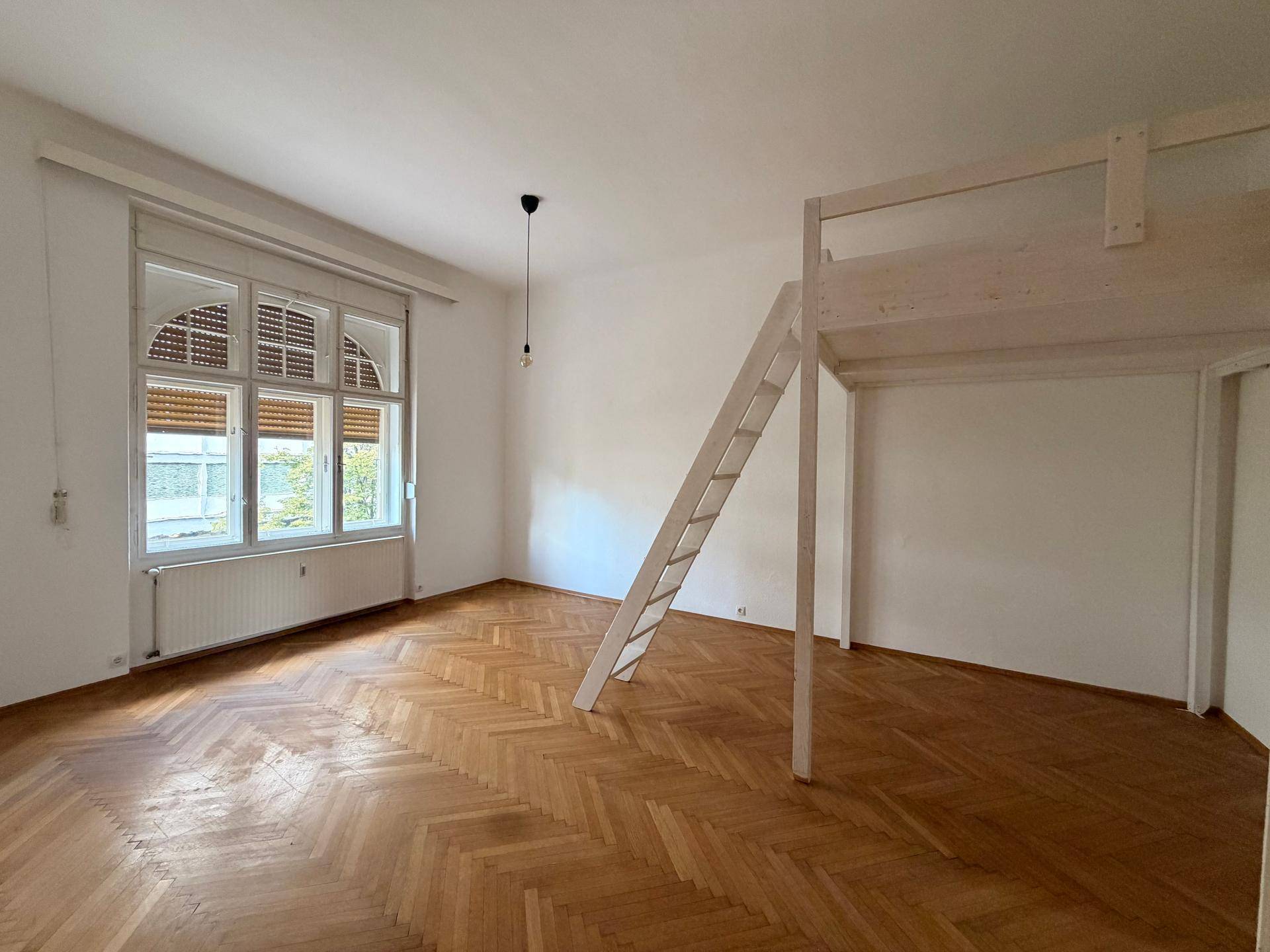 Helles Schlafzimmer mit Fischgrätparkett, großen Fenstern und einer Hochbettkonstruktion.