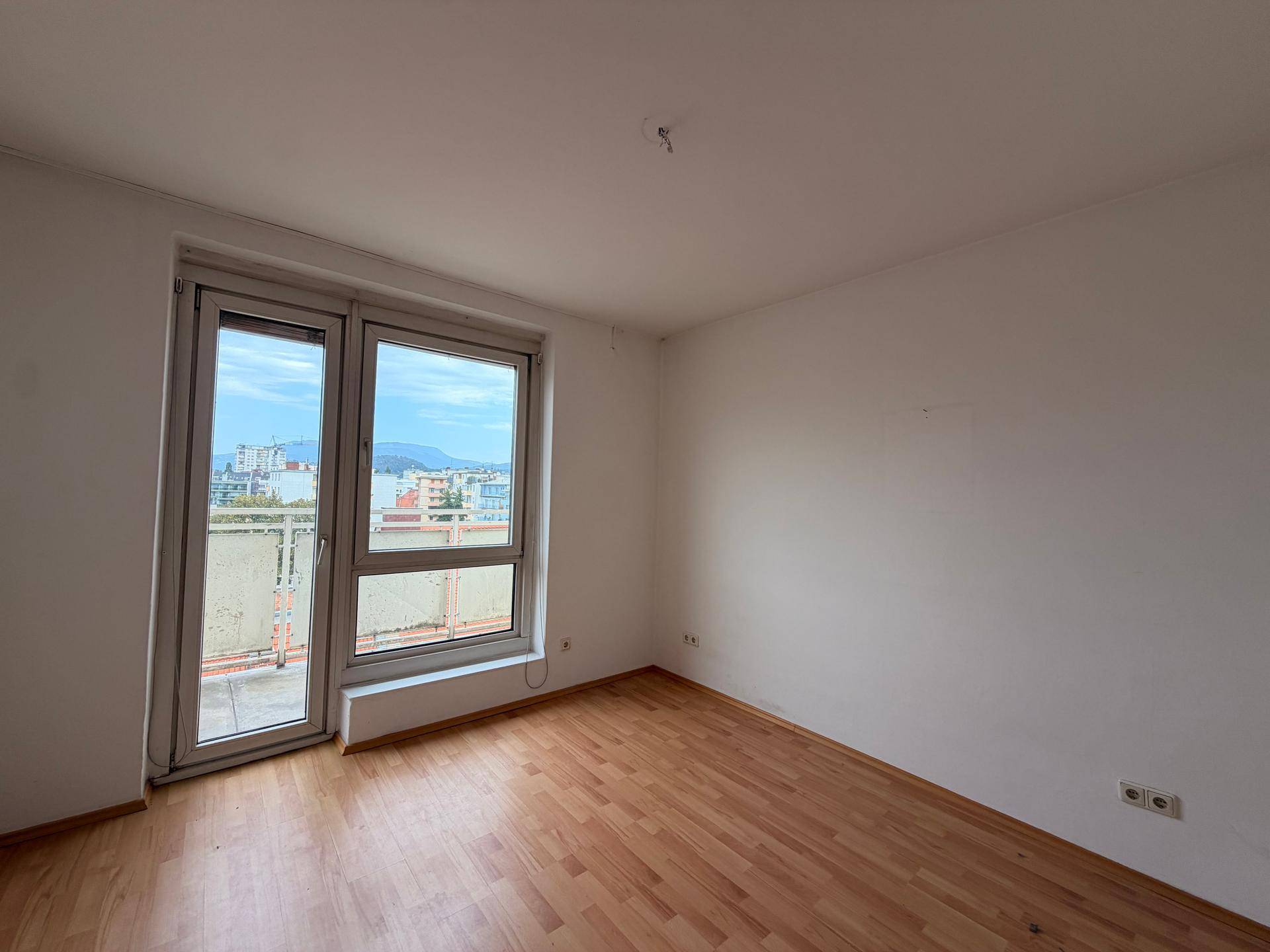 Geräumiges Zimmer mit Parkettboden und Zugang zu einem potenziellen Außenbereich.