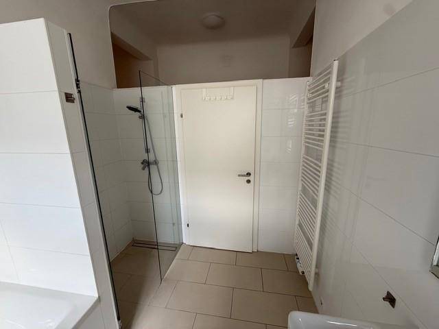 Modernes Badezimmer mit Dusche, beheiztem Handtuchhalter und Fliesenboden.