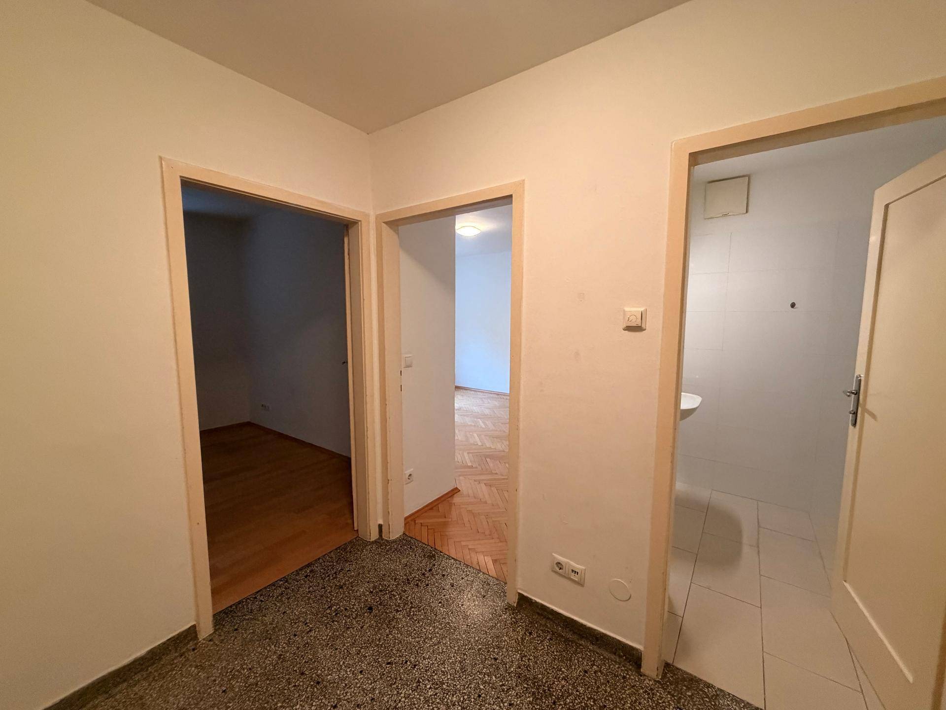 Flur mit mehreren Türen zu angrenzenden Räumen und einem dunklen Terrazzoboden.
