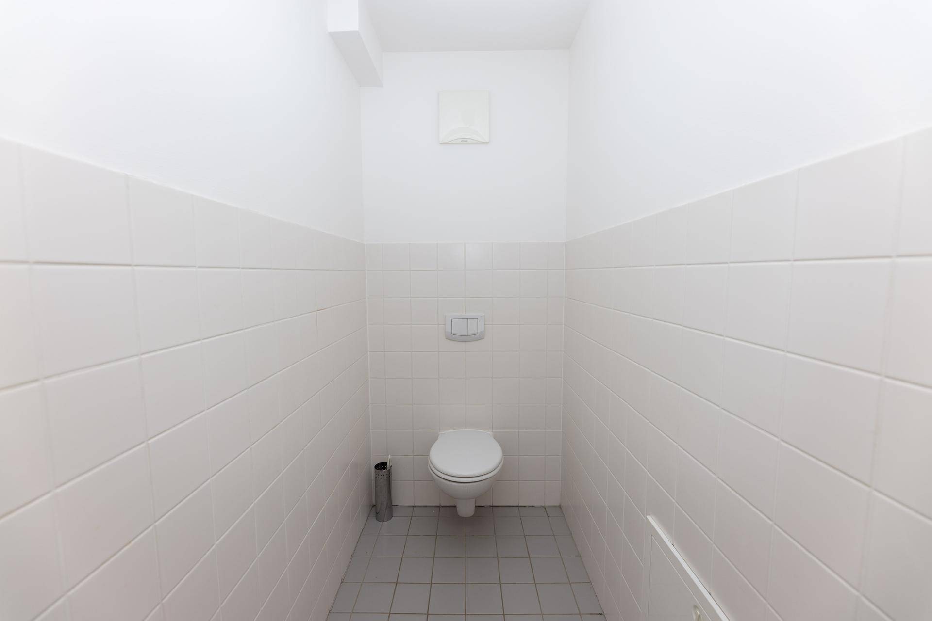 Separates WC mit Wand-WC und Fliesenboden.