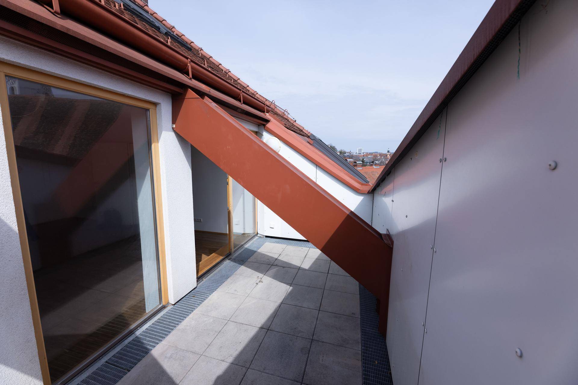 Dachterrasse mit Fliesenboden und Blick auf die umliegenden Dächer.
