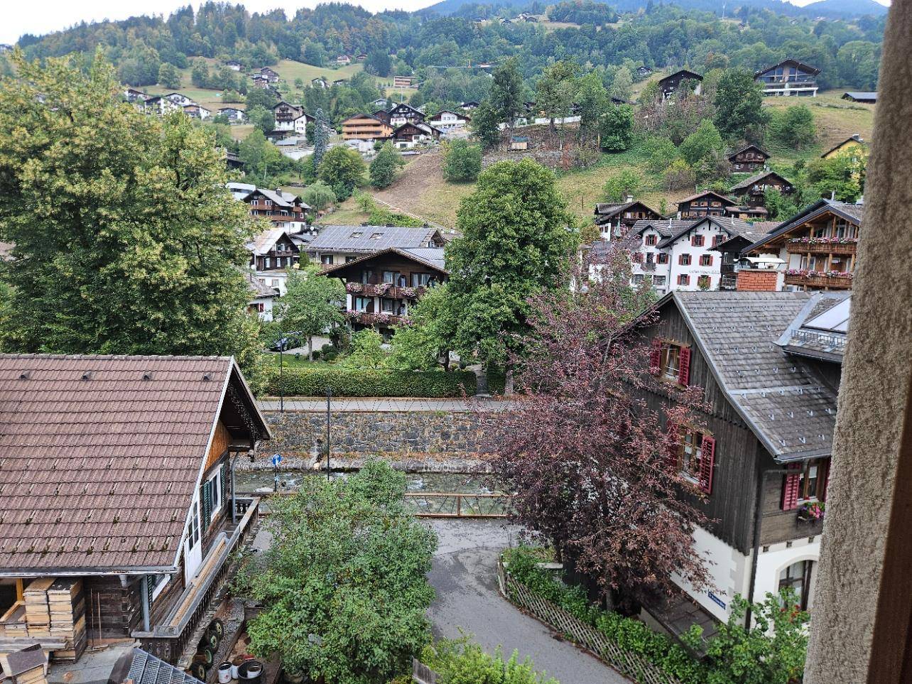 Panoramablick auf ein malerisches Dorf in den Bergen mit traditionellen Häusern und grüner Landschaft.