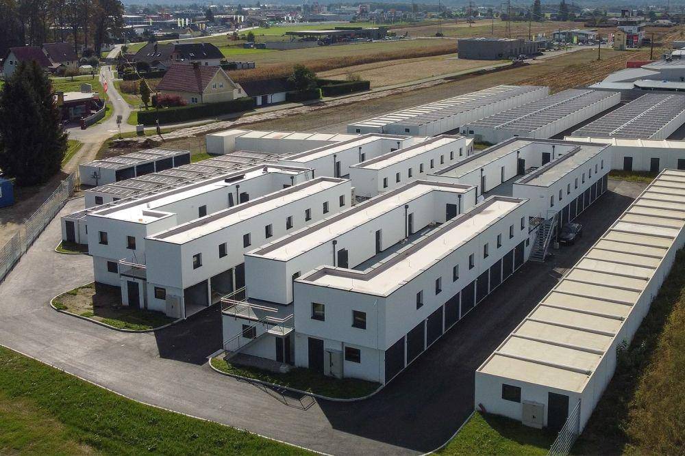 Luftaufnahme einer Anlage mit mehreren modernen Modulgebäuden und umliegender Infrastruktur in einer ländlichen Umgebung.