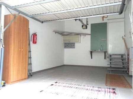 Geräumige Garage mit Stauraum und Fliesenboden, ideal für Fahrzeuge und Lagerung.