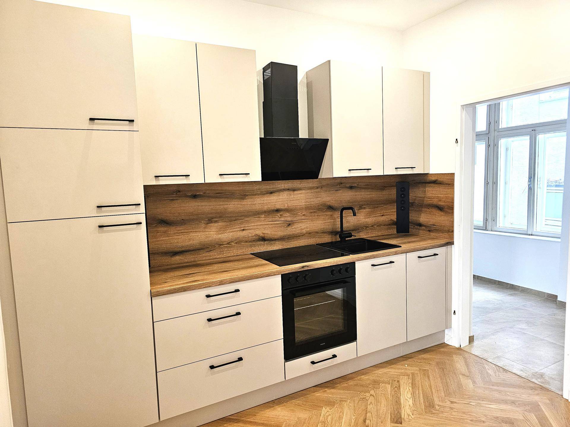 Moderne Einbauküche mit hellen Schränken, Holzakzenten und integrierten Geräten, in neuwertigem Zustand.