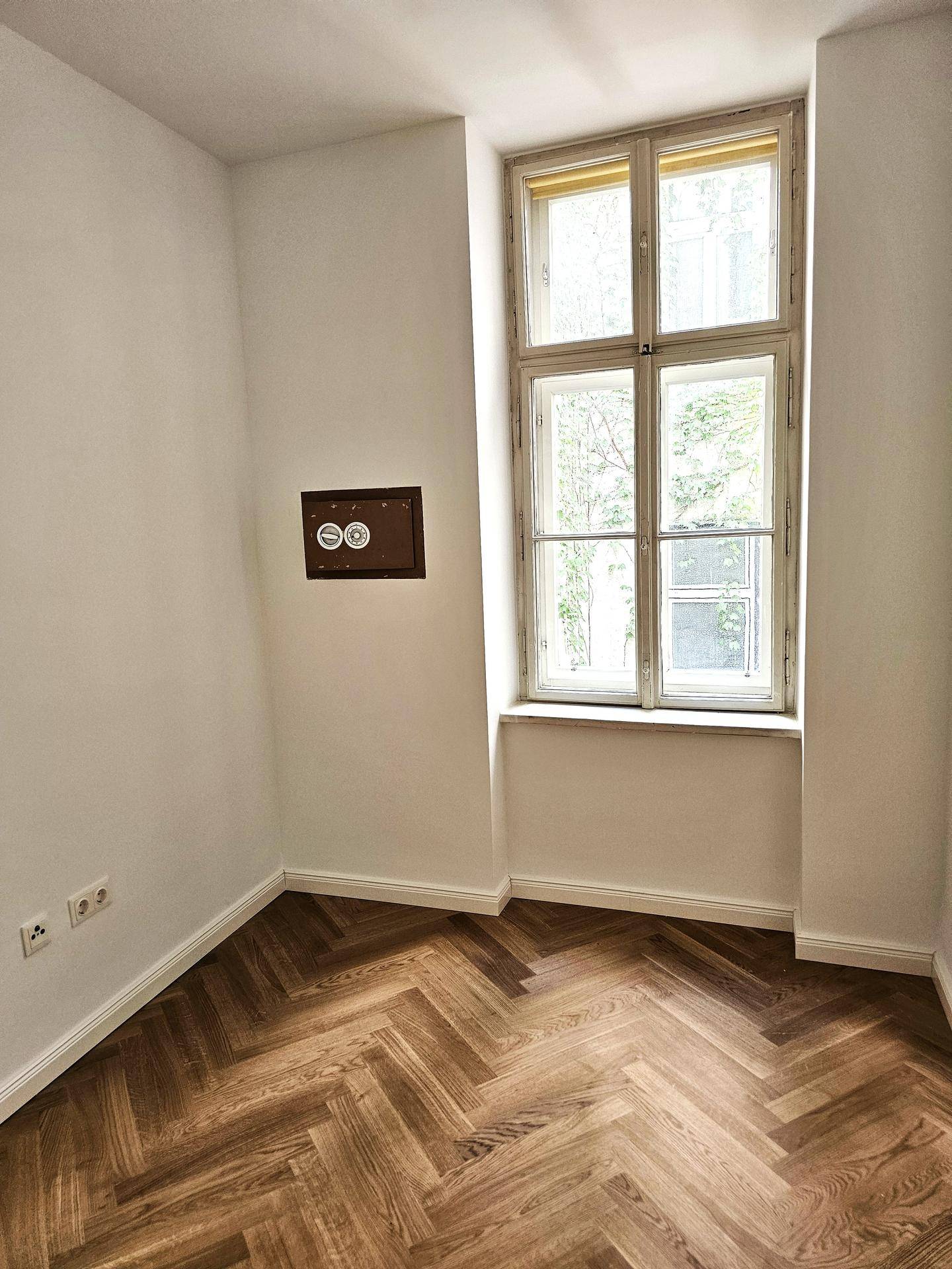 Kleiner Raum mit Fischgrätparkett und einem Fenster, ideal als Schlaf- oder Arbeitszimmer mit viel Tageslicht.