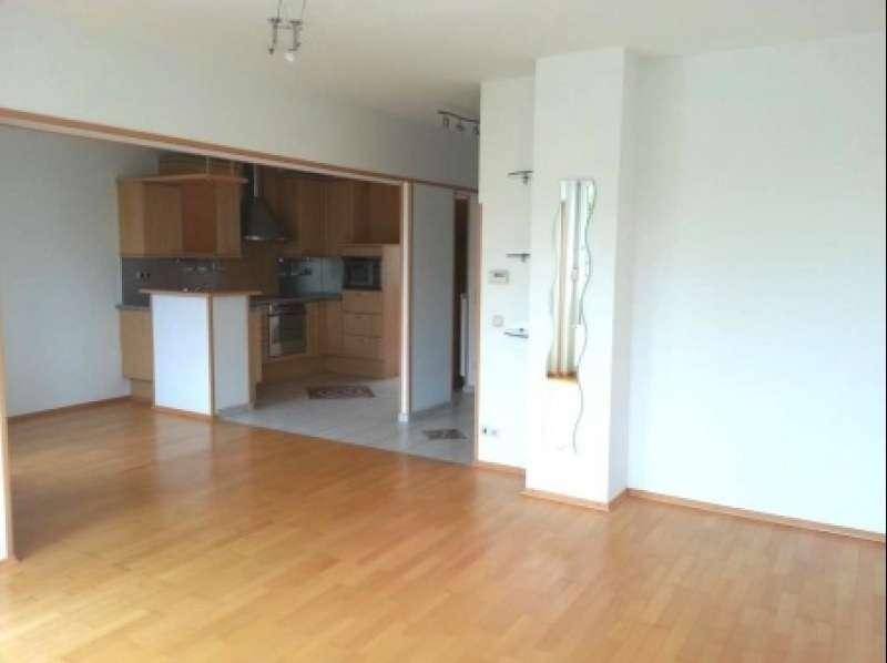 Geräumiges Wohnzimmer mit hellem Parkettboden und offenem Übergang zur Küche.
