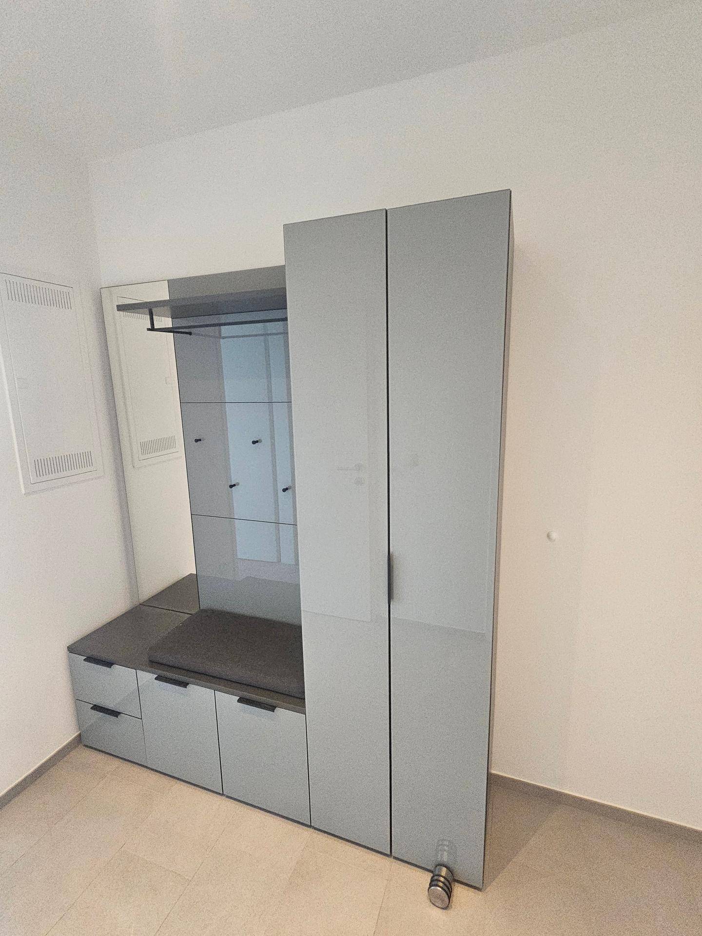 Moderner Garderobenschrank in Grau mit Sitzbank, Schubladen und Spiegel im Eingangsbereich.