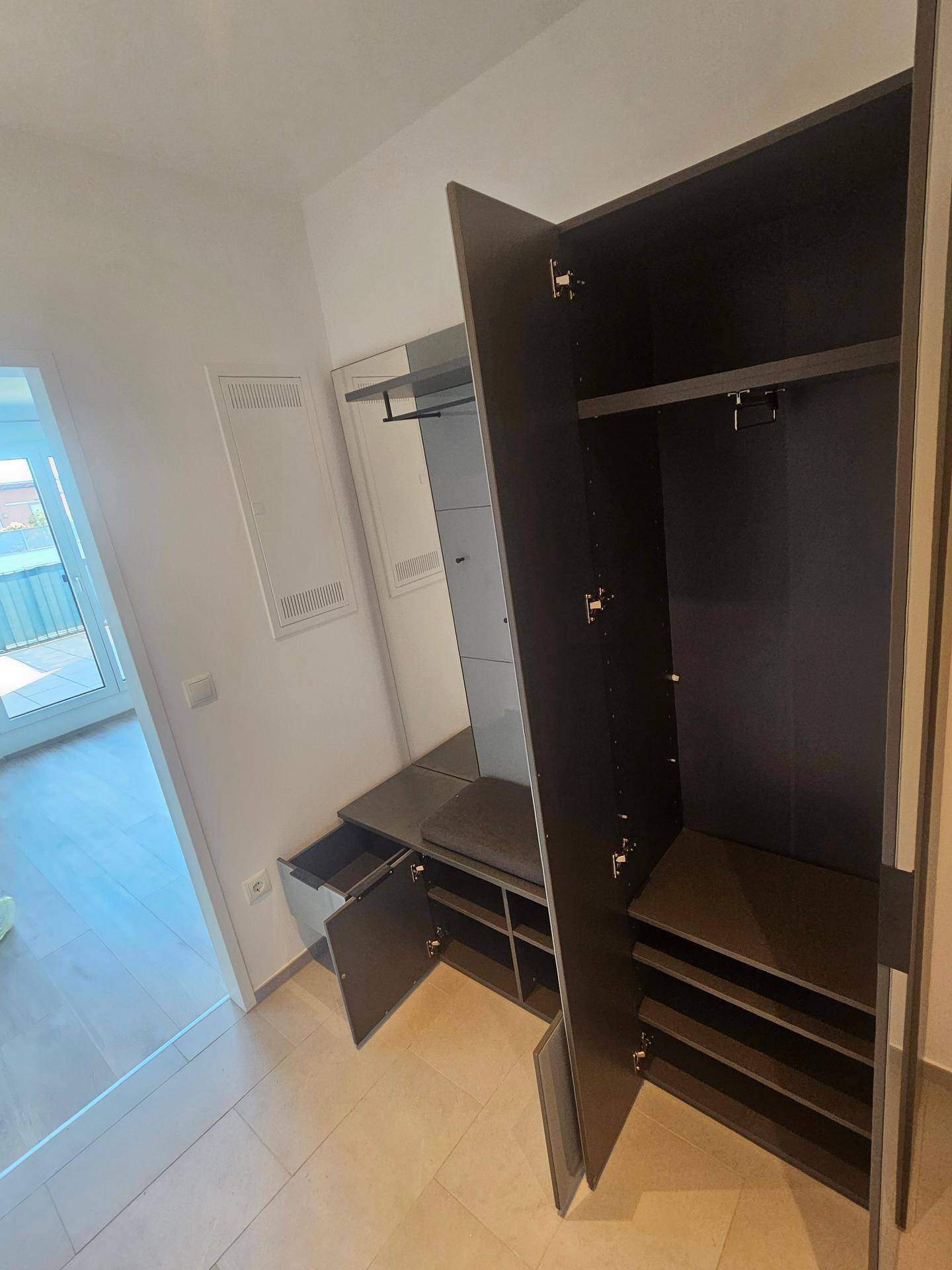 Offener Garderobenschrank in Grau mit praktischen Ablageflächen und Kleiderstange im Flur.