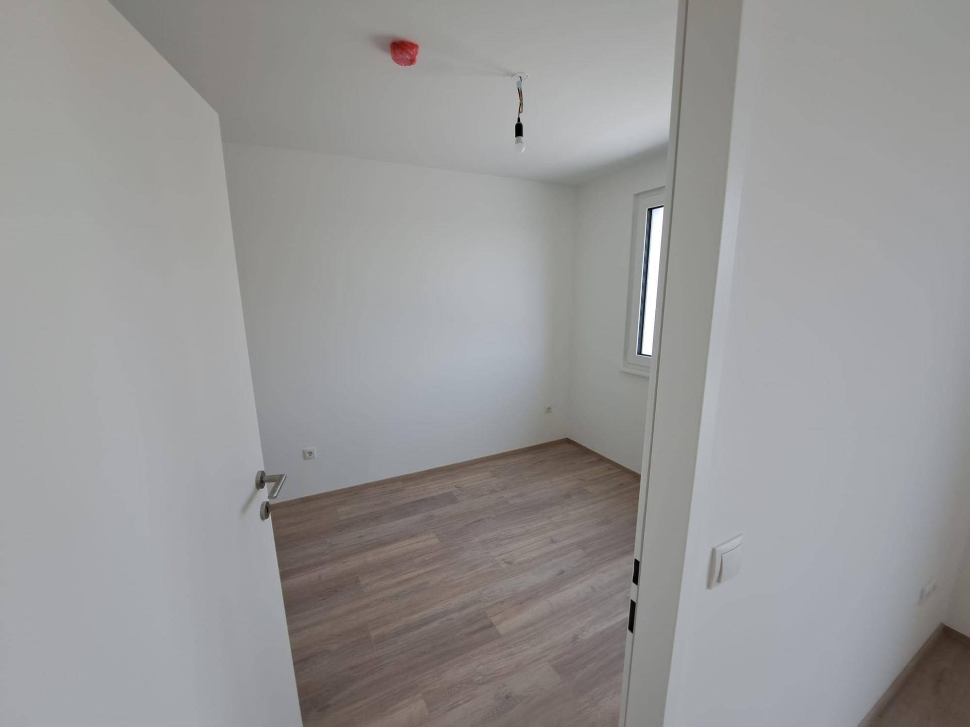 Helles Zimmer mit Laminatboden und weiß gestrichenen Wänden, ideal als Schlaf- oder Arbeitszimmer.