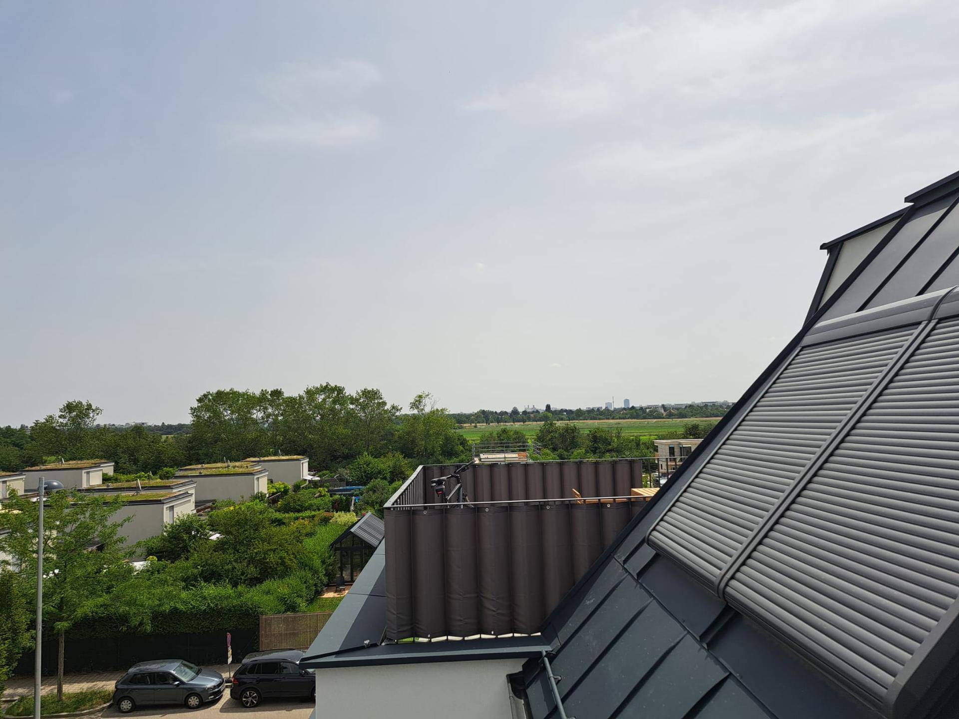 Dachansicht mit Rollläden und weitem Blick über eine grüne Landschaft unter klarem Himmel.