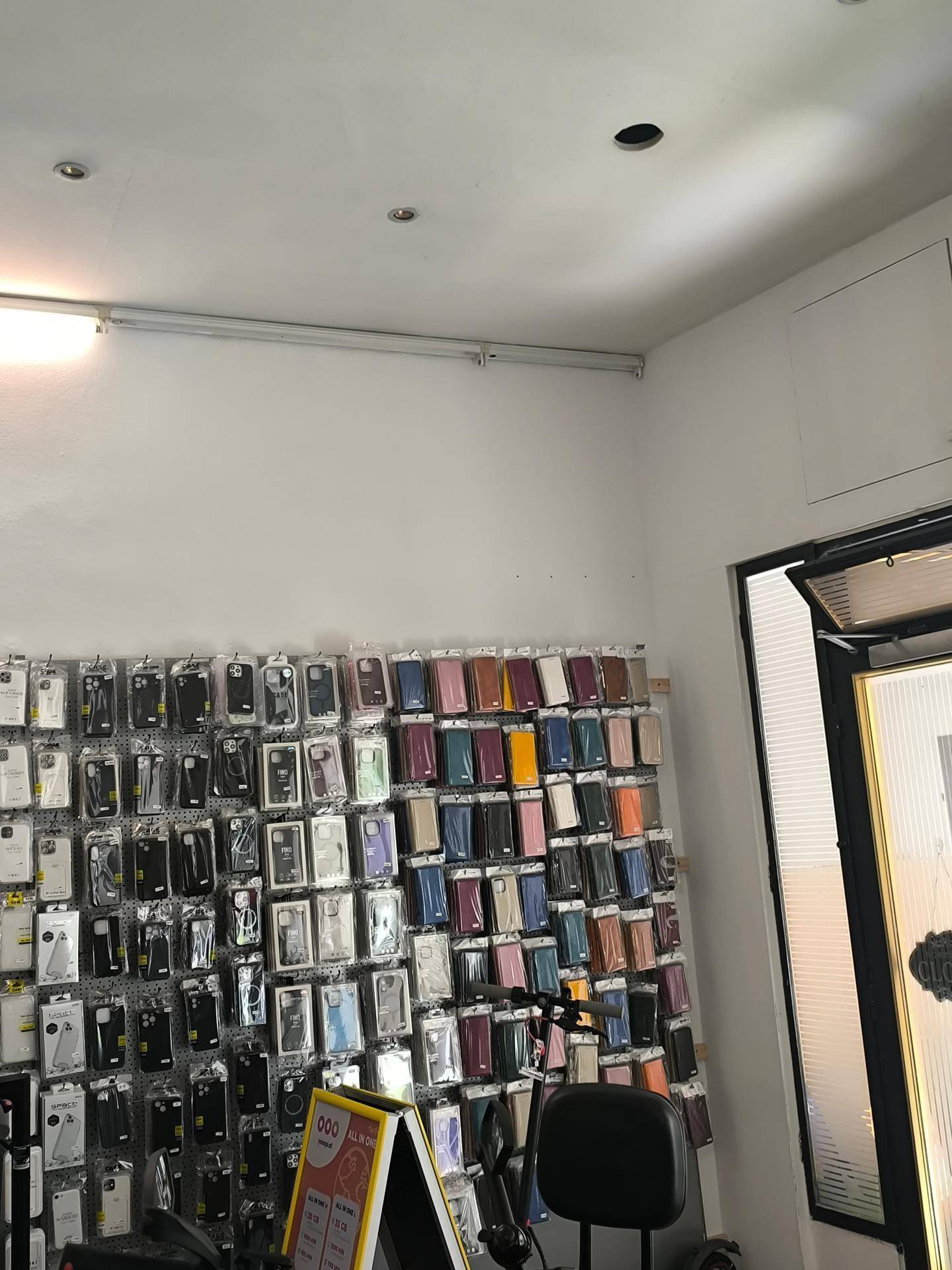 Innenansicht eines Verkaufsraums mit einer Wand voller Handyhüllen und moderner Deckenbeleuchtung.