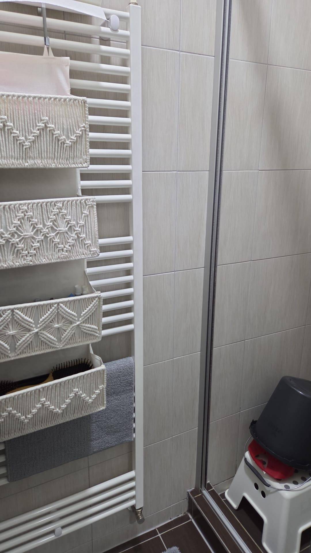 Badezimmer mit Duschkabine und einem weißen Handtuchheizkörper an der Wand.