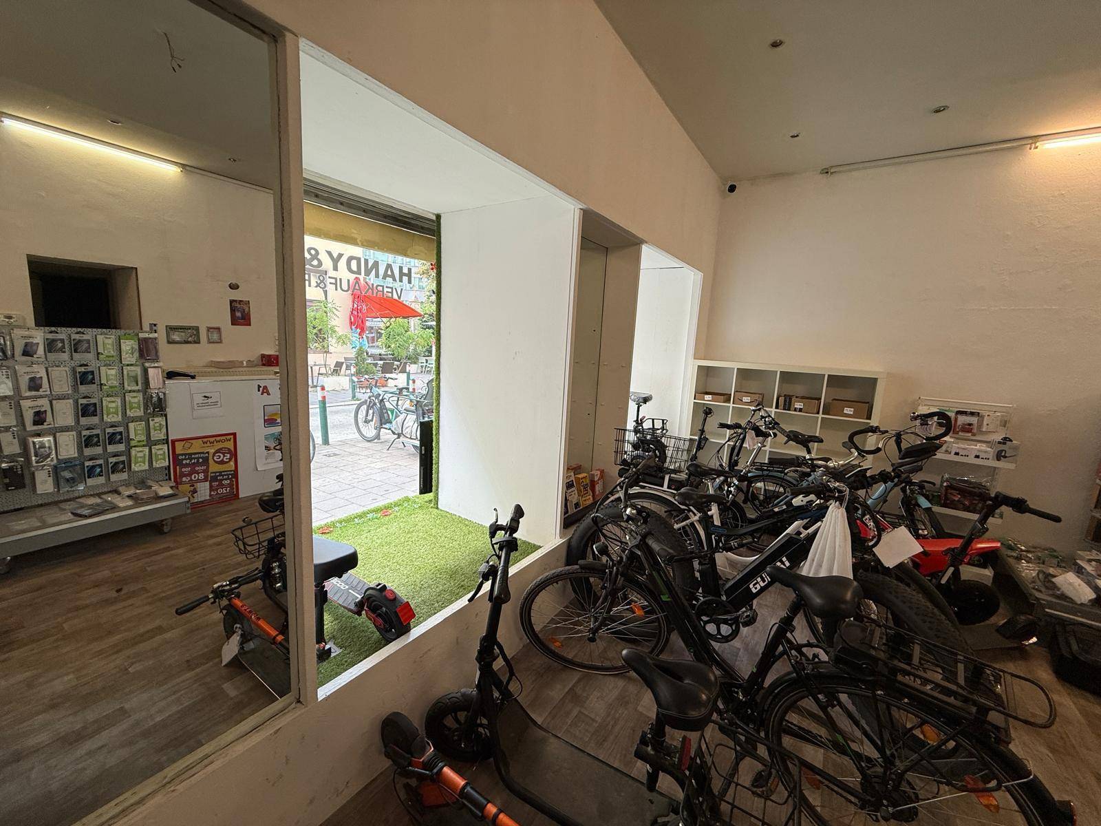 Geräumiger Verkaufsraum mit Fahrrädern und E-Scootern, einem großen Schaufenster und Holzfußboden.