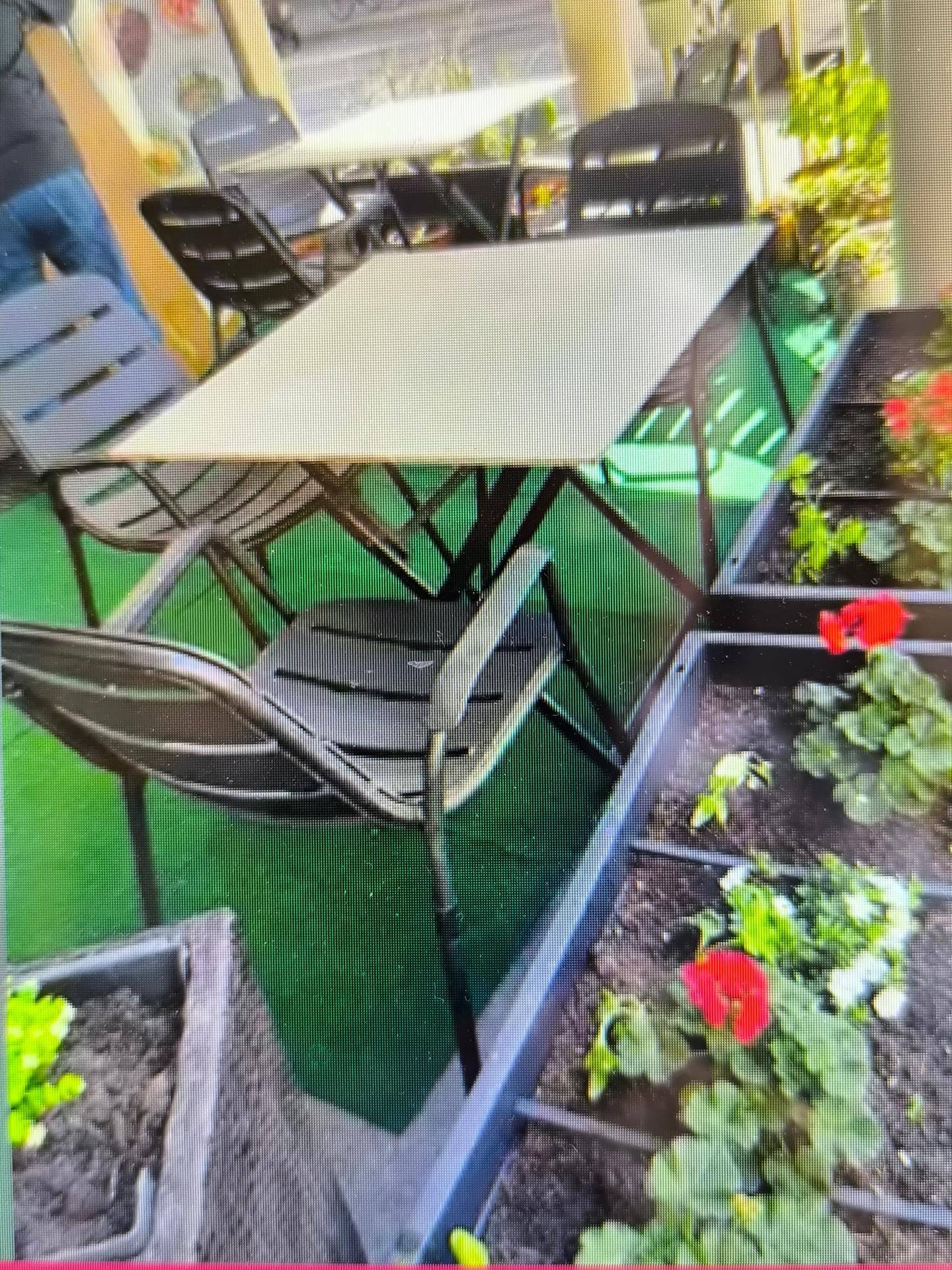 Außenbereich mit Tischen, Stühlen und Blumenkästen, ideal für Mahlzeiten im Freien.
