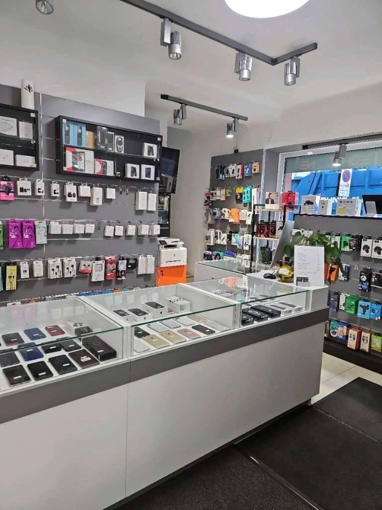 Innenansicht eines modernen Elektronikgeschäfts mit beleuchteten Vitrinen und zahlreichen Handy-Accessoires.