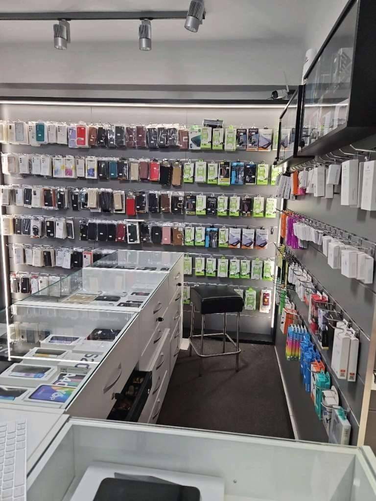 Blick in ein Elektronikgeschäft mit einer großen Auswahl an Handyhüllen und Zubehör in Wandregalen.