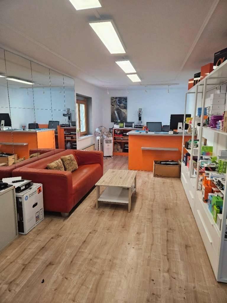 Geräumiger Arbeitsbereich mit Wartebereich, Ledersofa, Holzboden und mehreren Computerarbeitsplätzen.