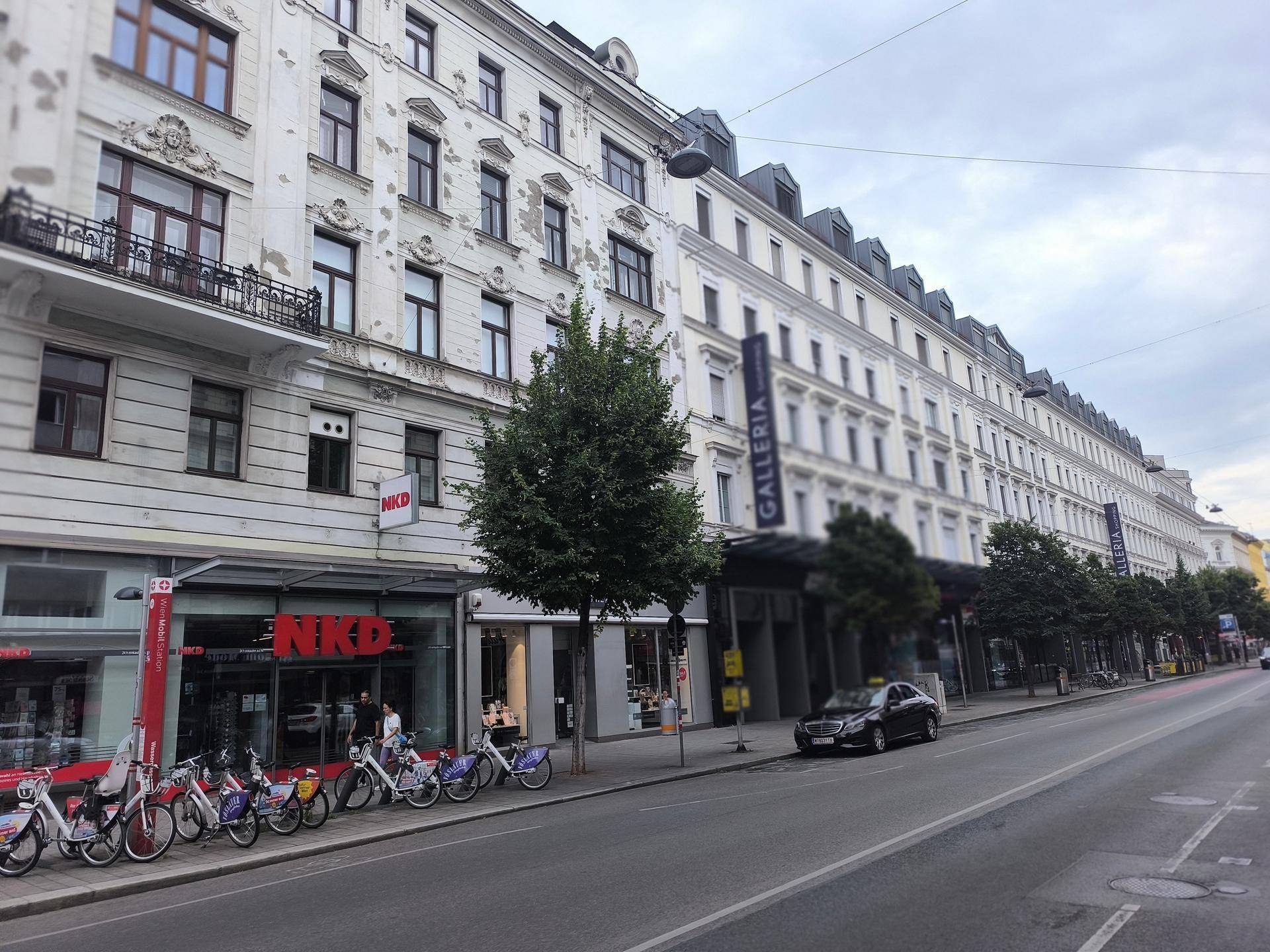 Weitläufige Stadtansicht mit einer langen Gebäudereihe, Geschäften und vielen Fahrrädern am Straßenrand.