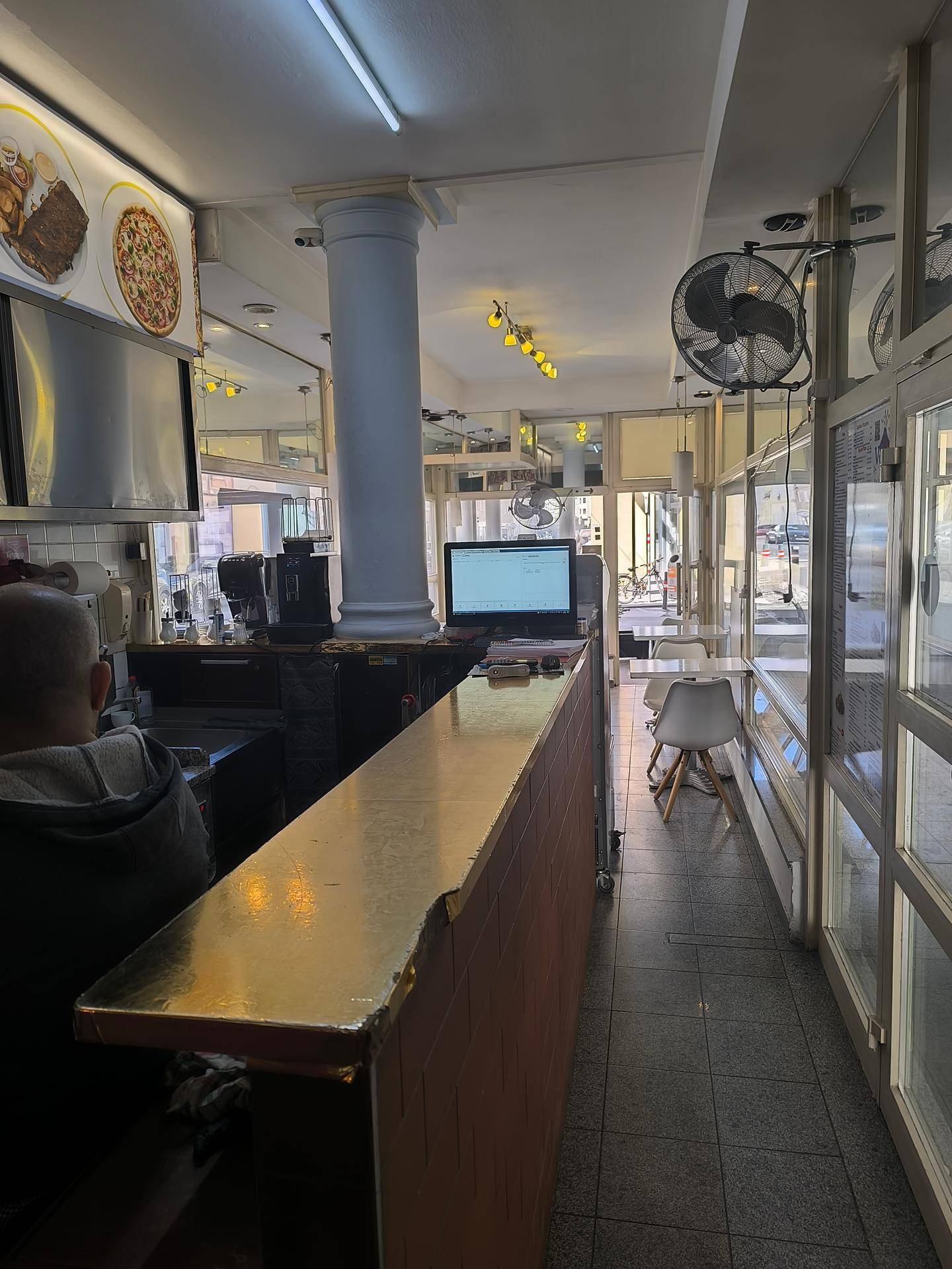 Innenansicht des Restaurants mit Theke, Sitzbereich und Blick zur Straße.