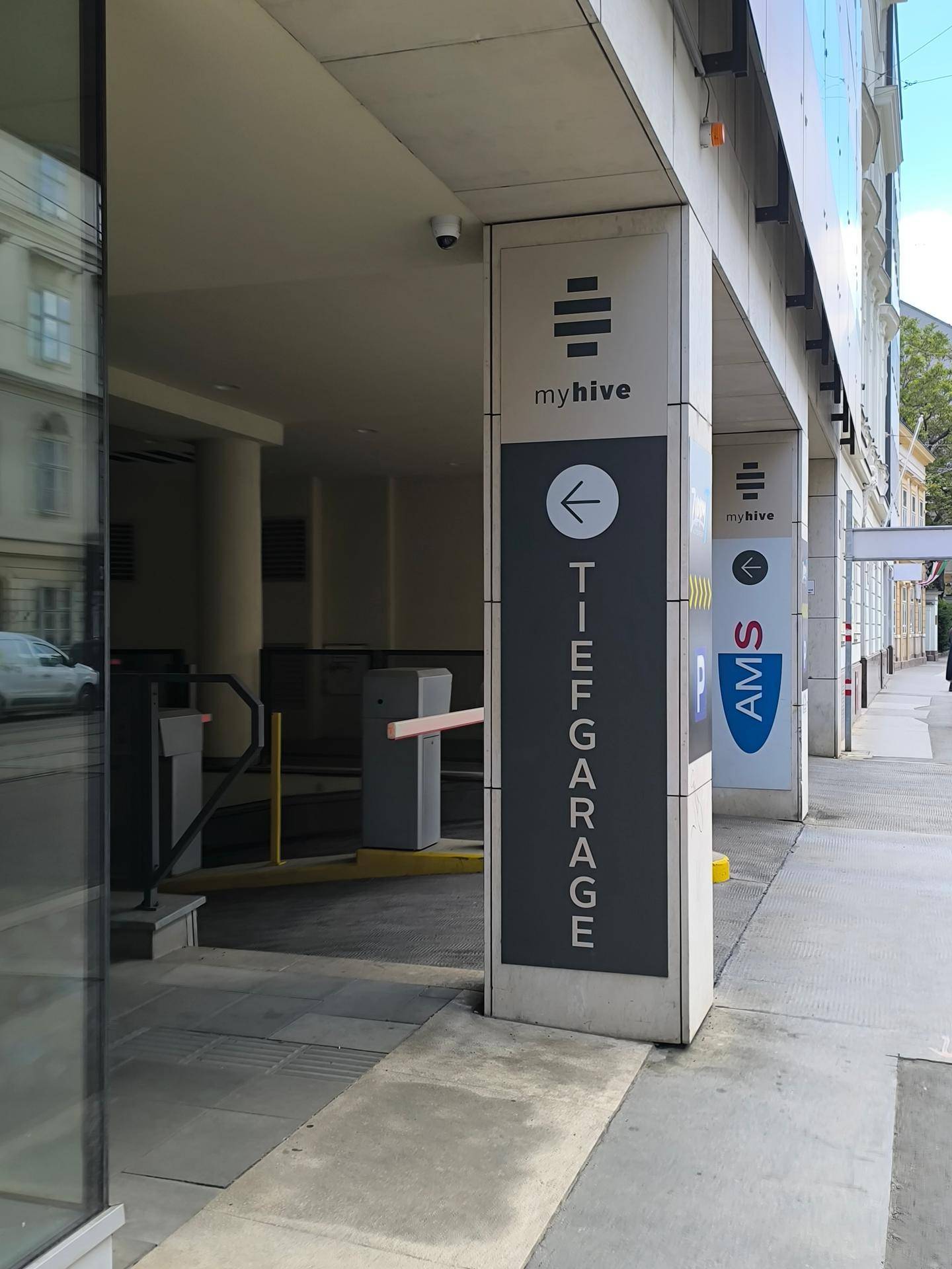 Eingangsbereich einer Tiefgarage mit Schranken und Hinweisschildern für Parkmöglichkeiten.