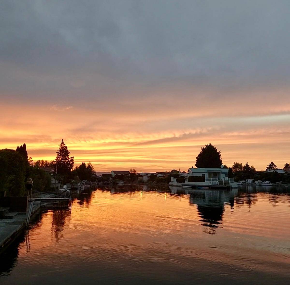 Spektakulärer Sonnenuntergang über dem See mit leuchtenden Farben am Himmel und Wasser.