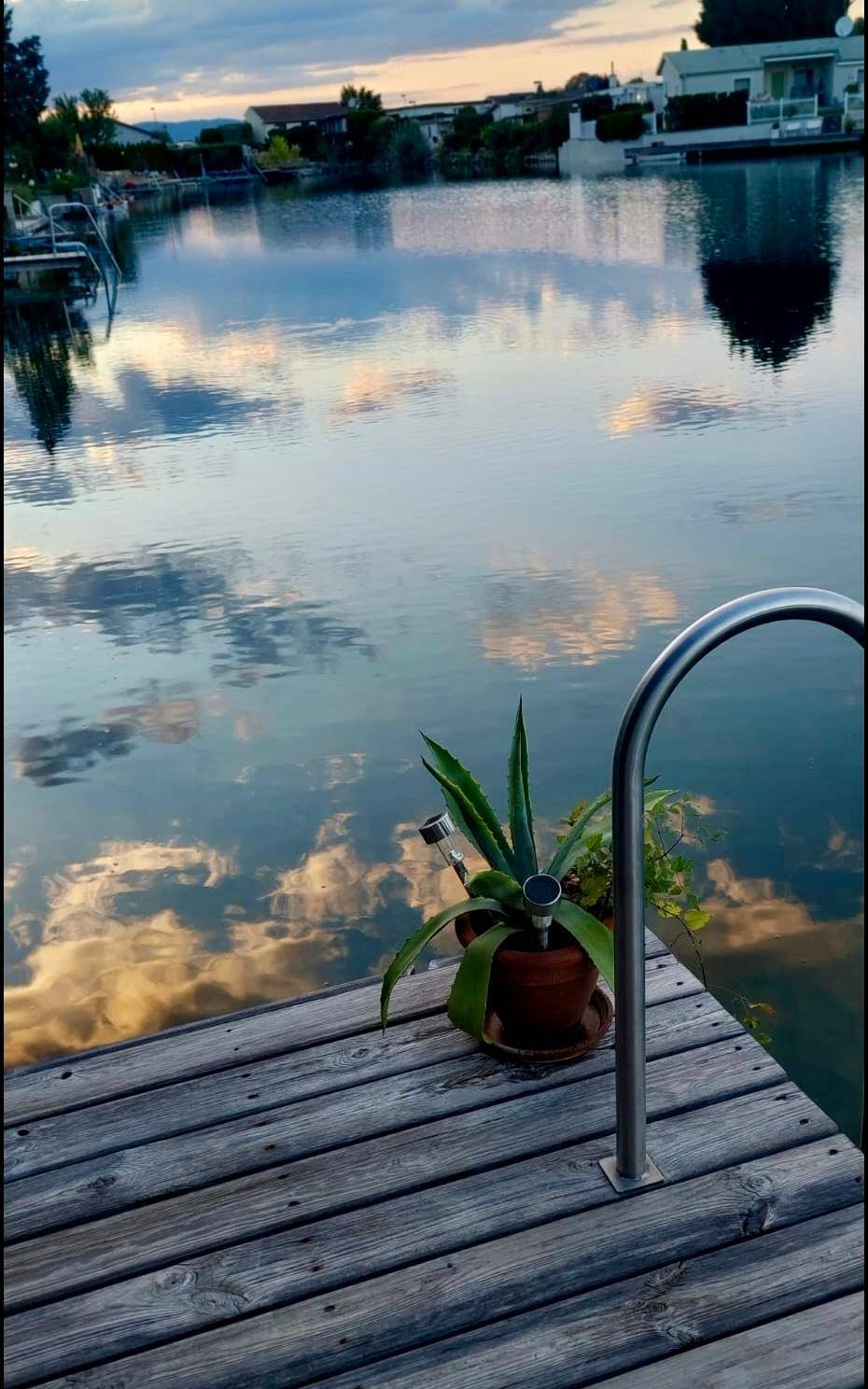 Ruhige Abendstimmung am See mit spiegelnden Wolken und Häusern am Ufer.