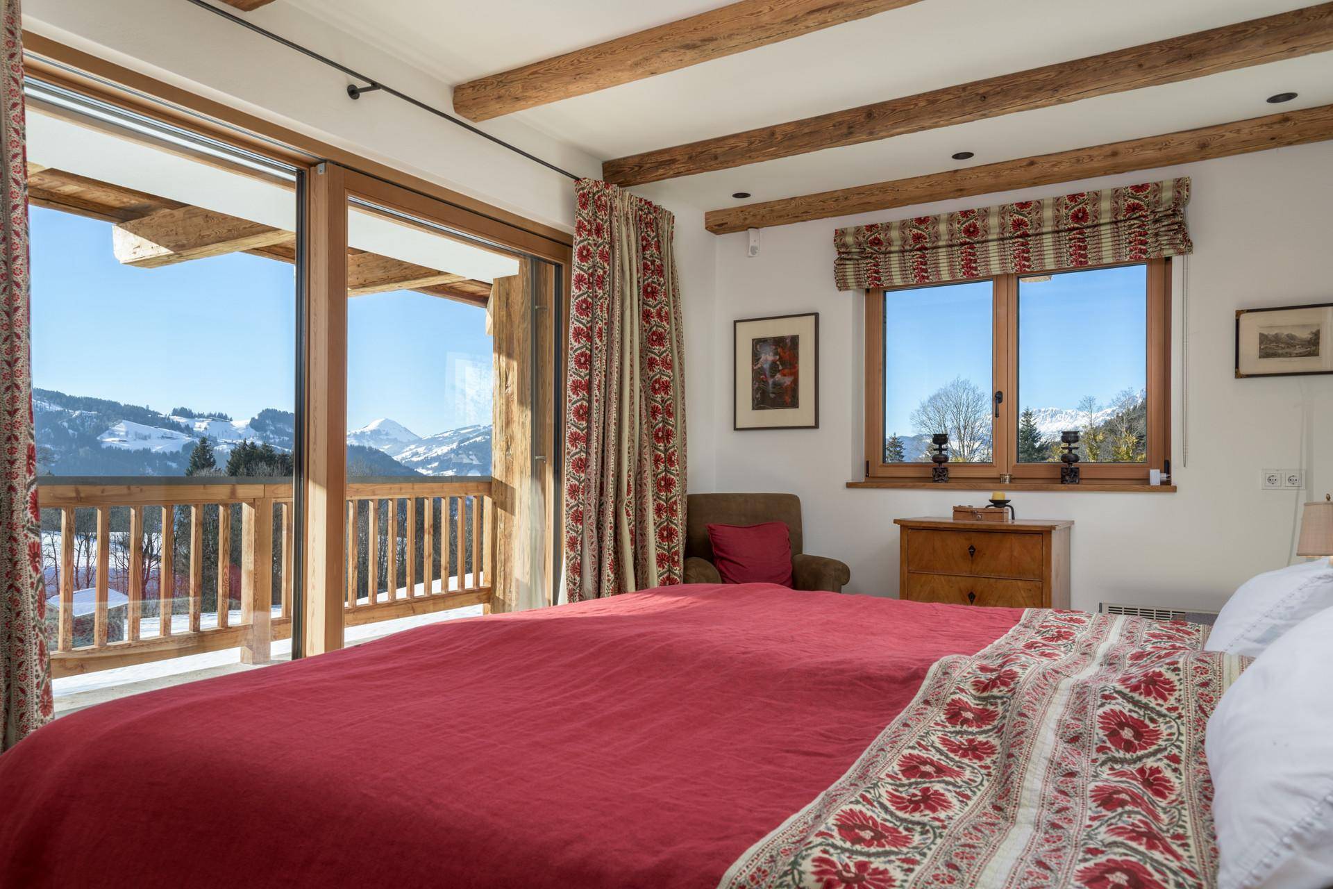 Schlafzimmer mit Balkonzugang, Bergblick und traditionellen Textilien.