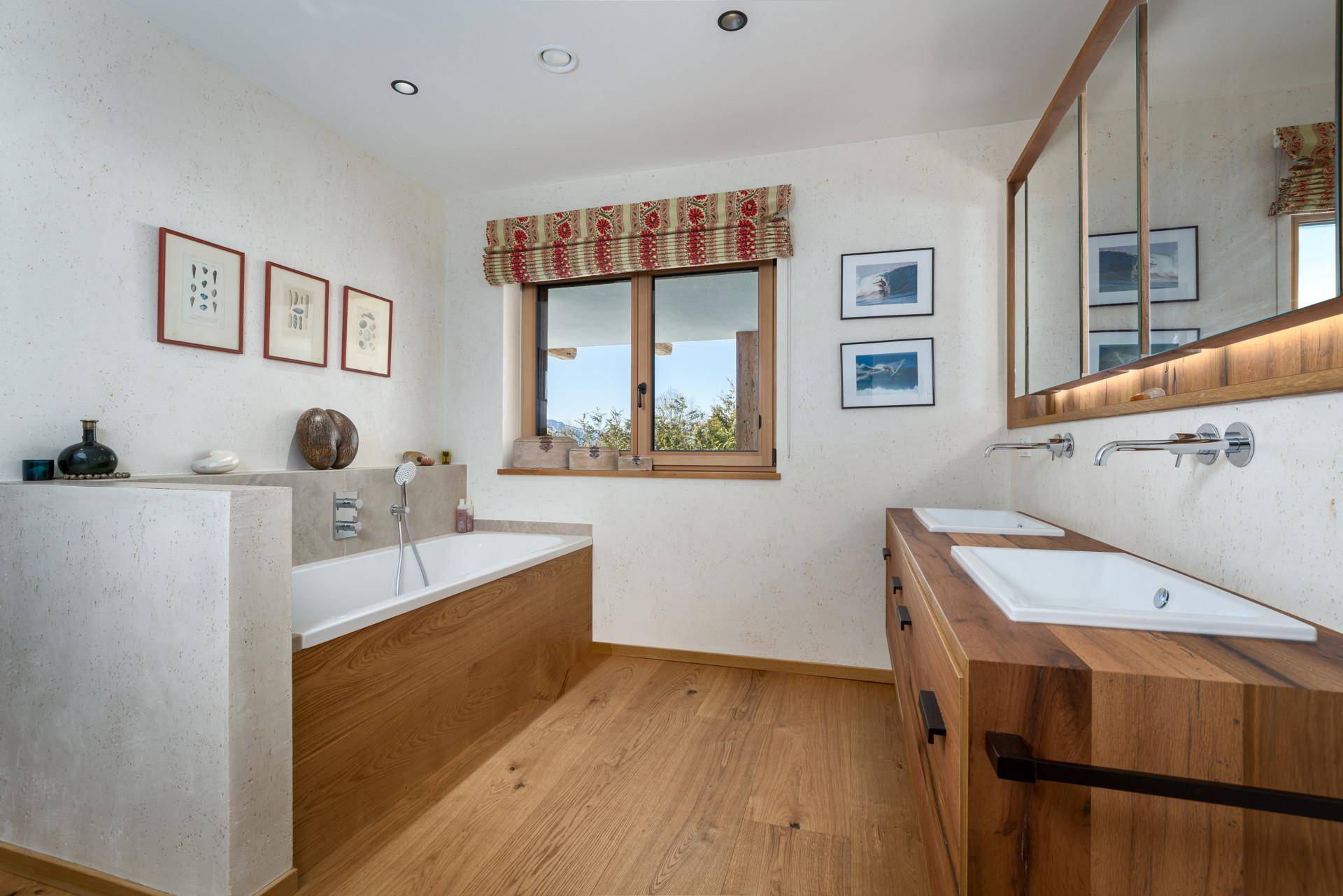 Modernes Badezimmer mit Doppelwaschbecken, Badewanne und Holzdetails.