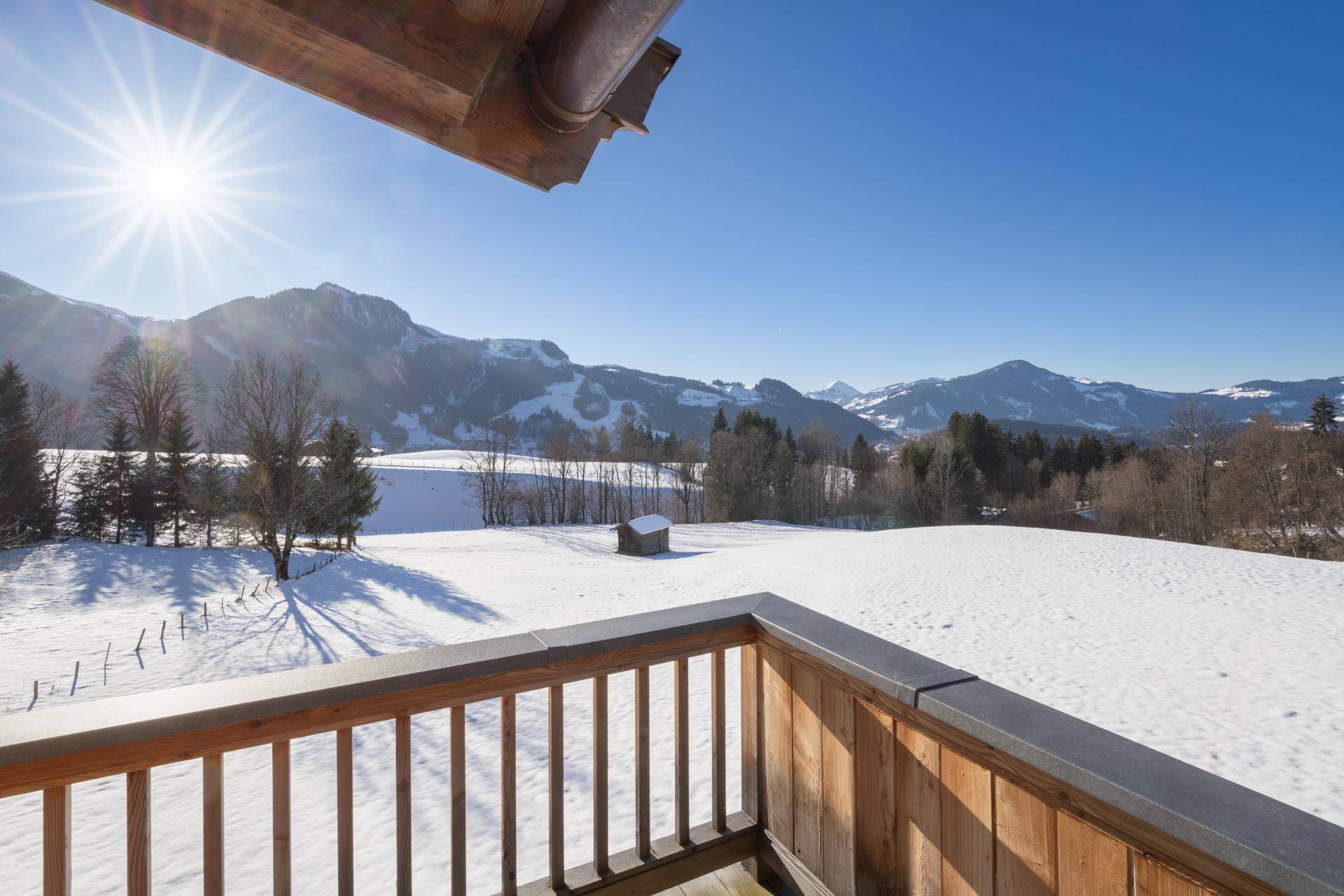 Sonniger Balkon mit weitem Blick über die verschneite Berglandschaft.