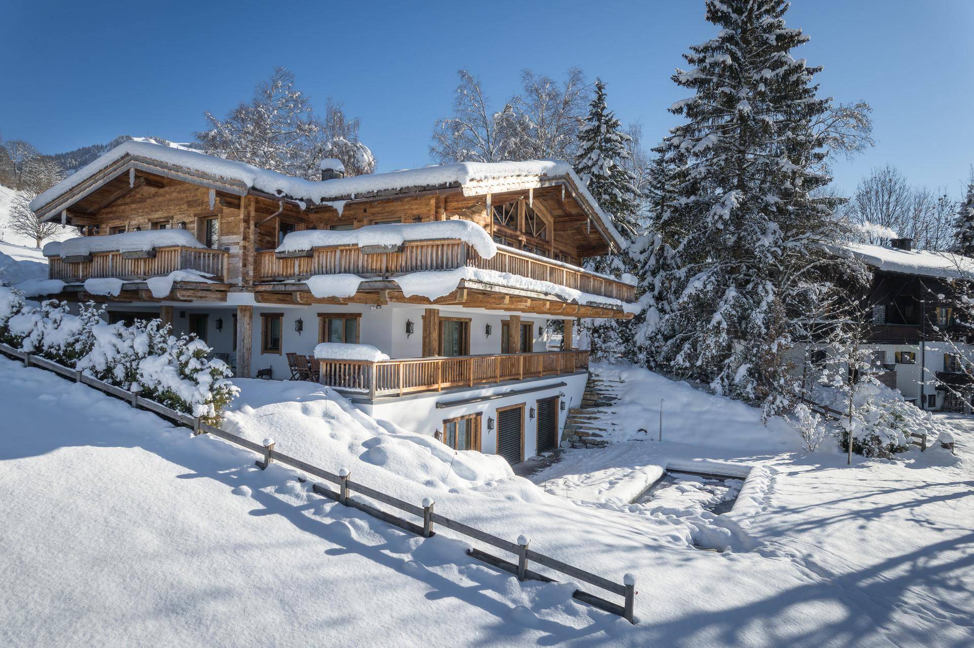 Großzügiges Chalet in winterlicher Umgebung mit schneebedeckten Balkonen und Bäumen.