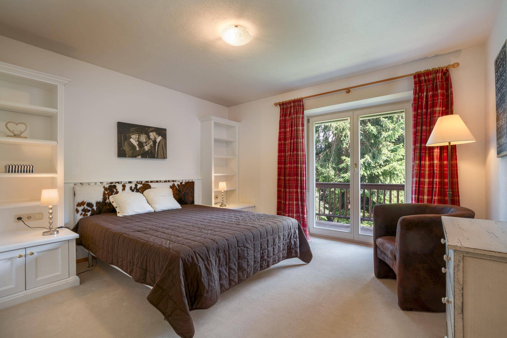 Gemütliches Schlafzimmer mit Teppichboden, Balkonzugang und Blick ins Grüne.