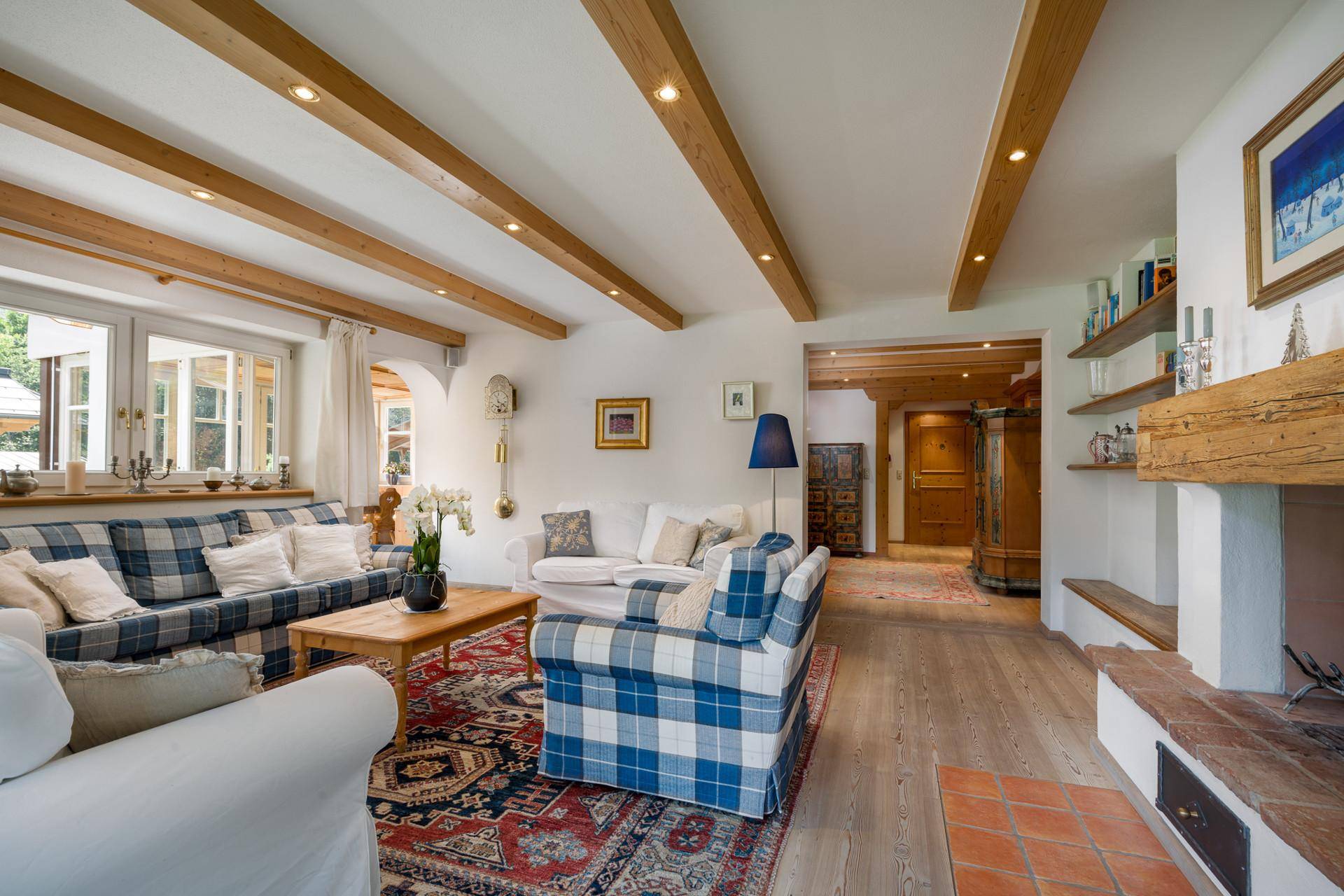 Geräumiges Wohnzimmer im Landhausstil mit Holzbalken, Kamin und gemütlichen Sitzgelegenheiten.