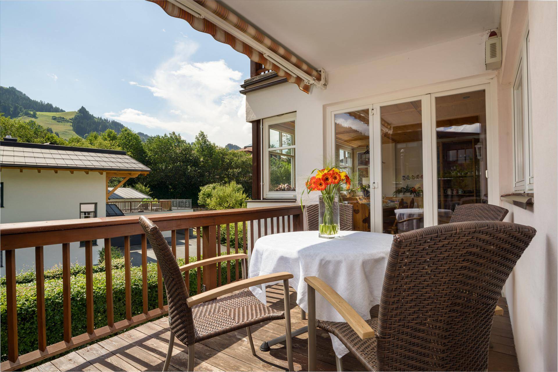 Sonniger Holzbalkon mit Sitzgelegenheiten, Markise und malerischem Bergblick.